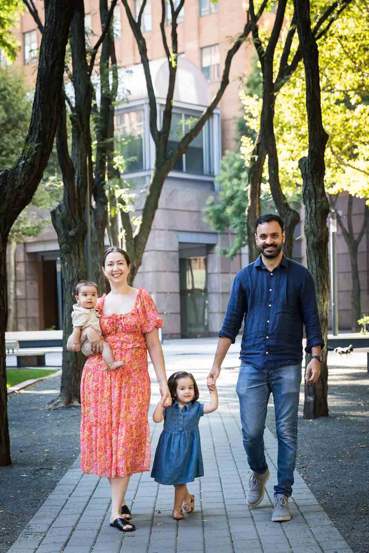 Parents with baby and little girl walking down stone pathway during a Brooklyn Commons family portrait session