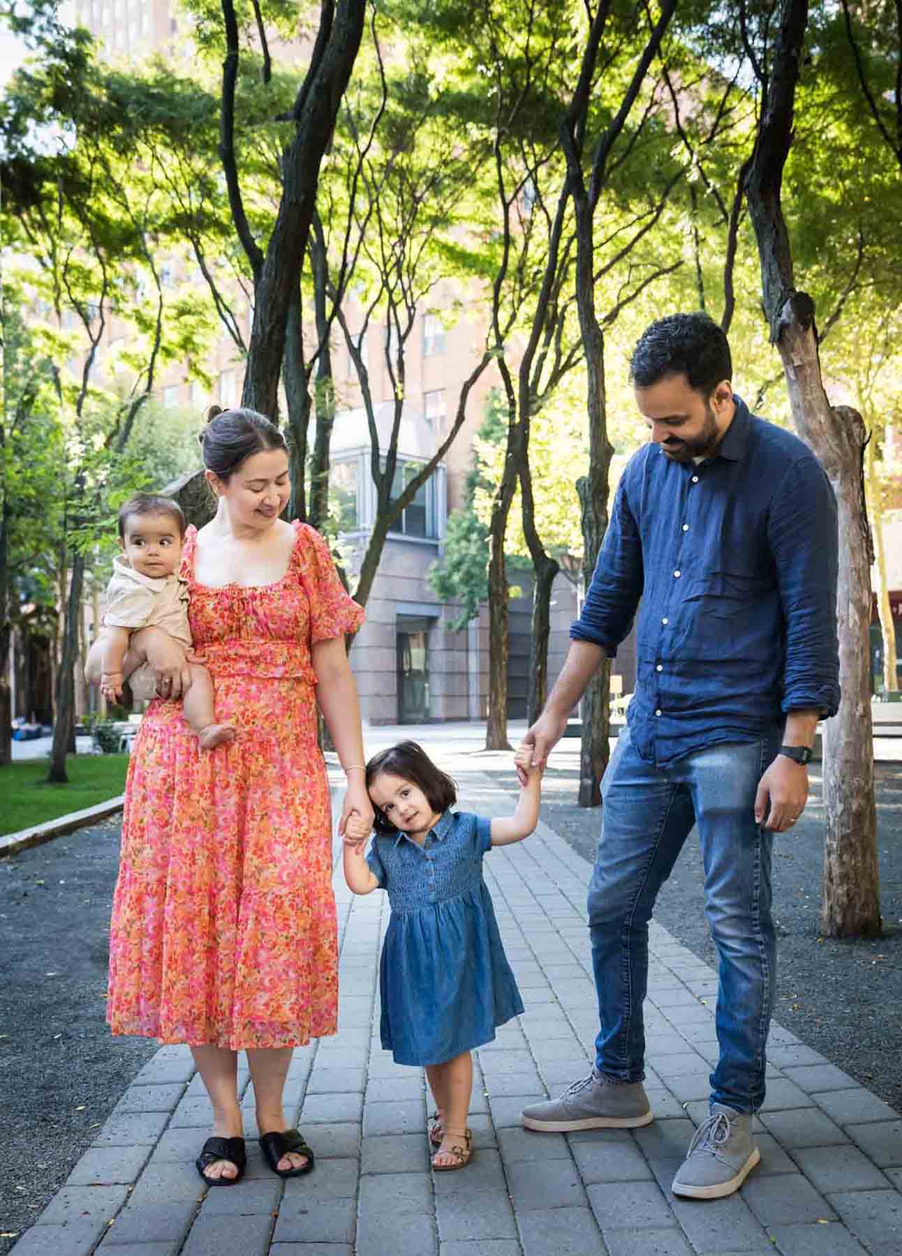 Parents with baby and little girl walking down stone pathway during a Brooklyn Commons family portrait session