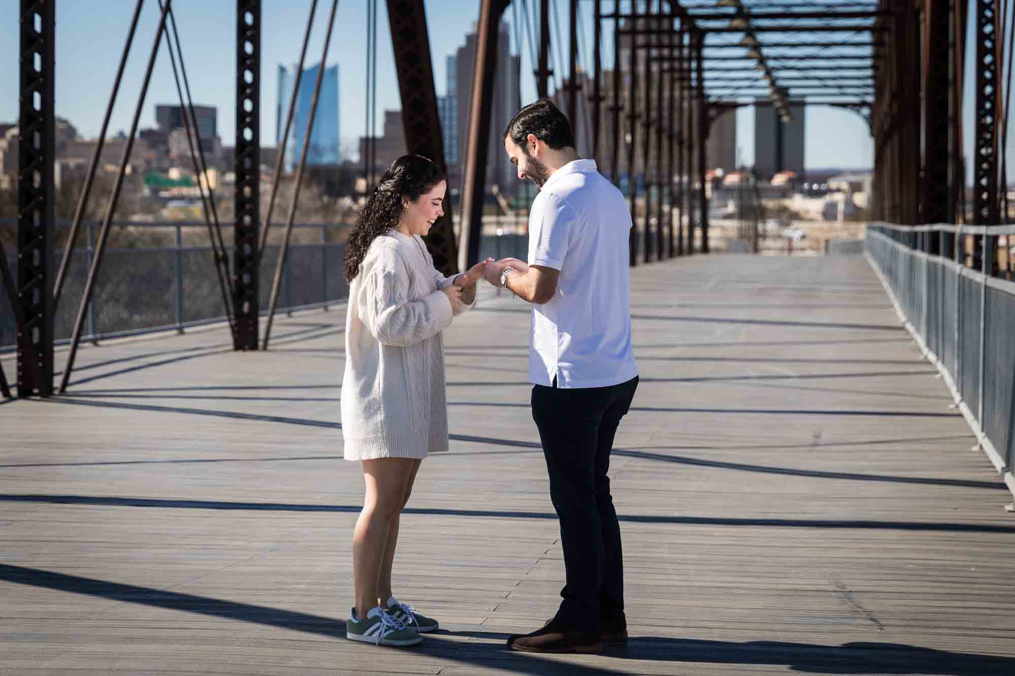Man putting ring on woman's hand during a Hays Street Bridge proposal