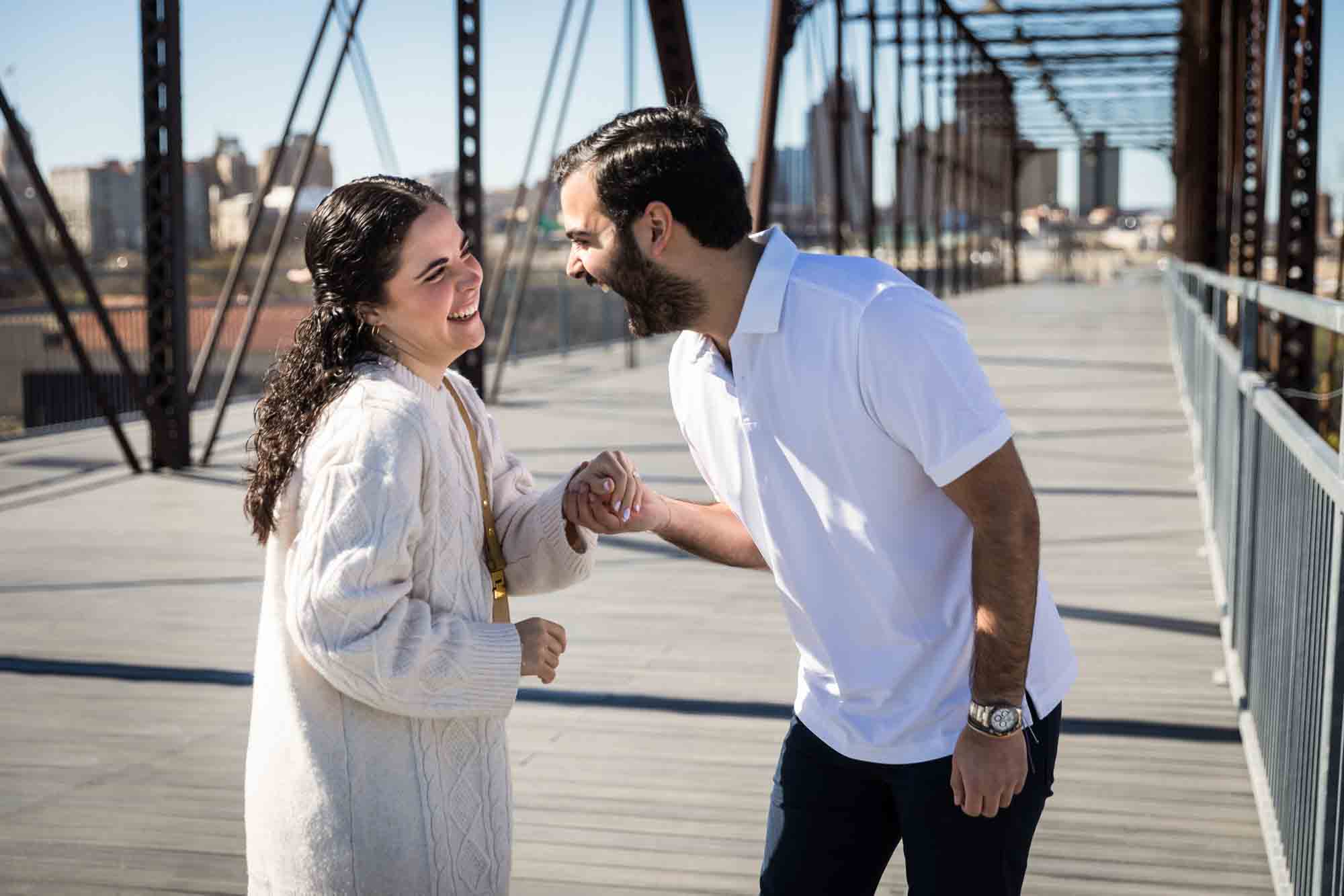 Couple holding hands and laughing during a Hays Street Bridge proposal