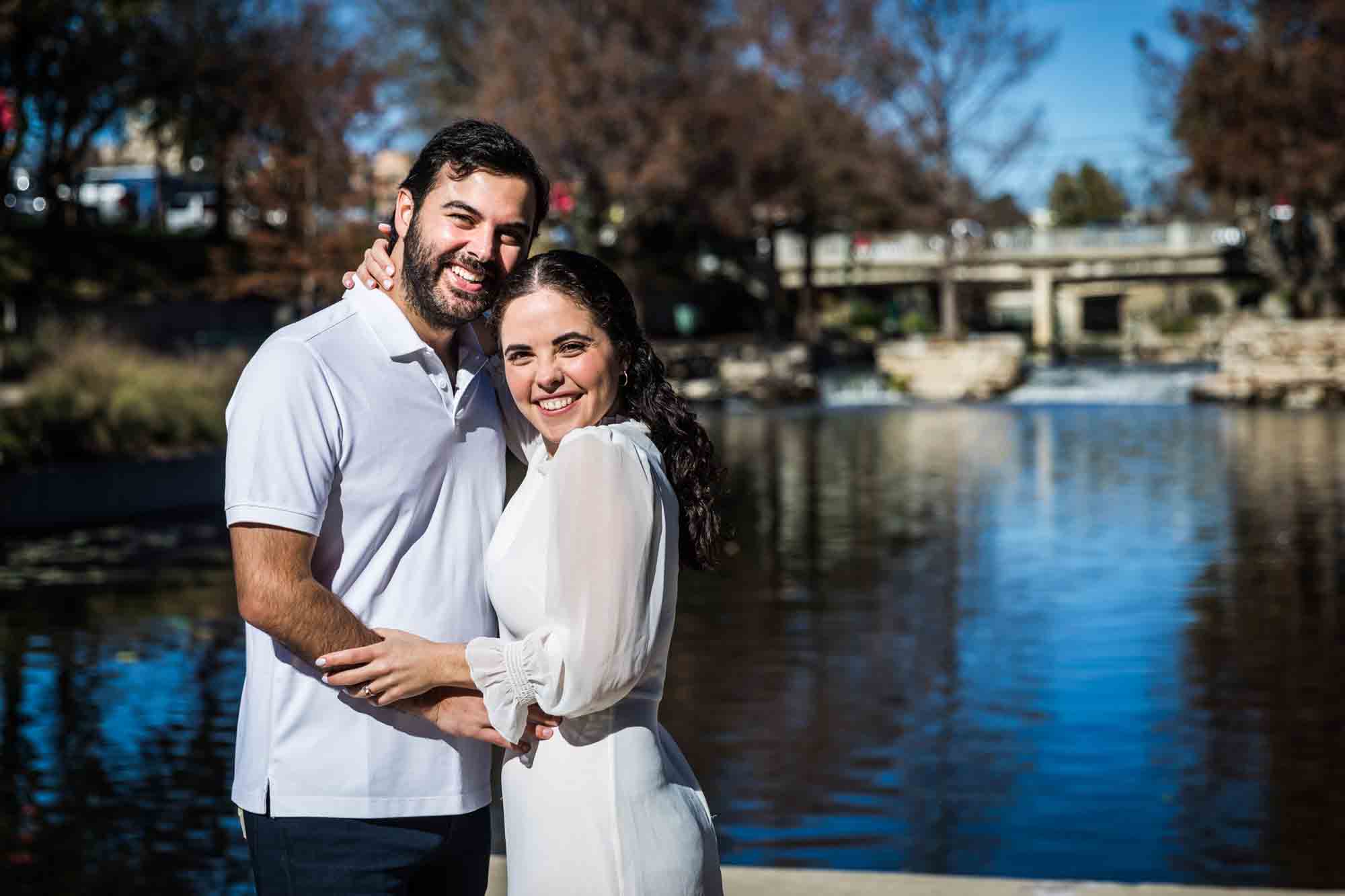 Couple hugging in front of the Riverwalk during a Pearl engagement portrait session