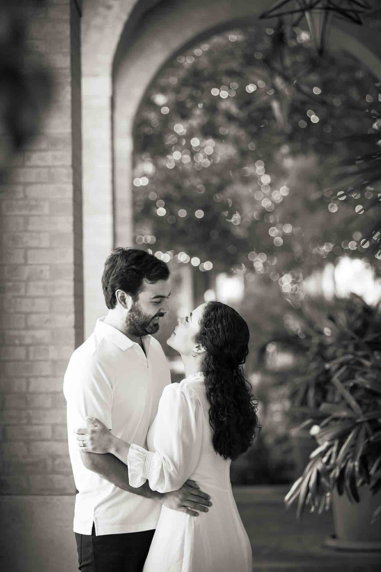 Black and white photo of couple hugging under brick archway during a Pearl engagement portrait session
