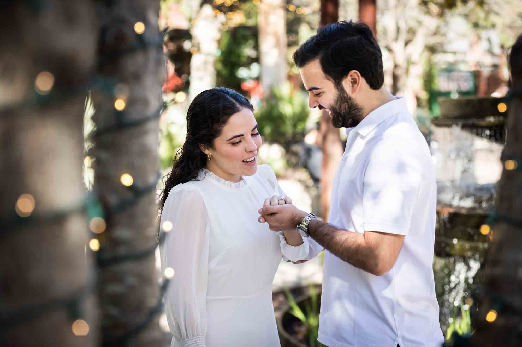 Couple looking down at woman's hand showing engagement ring during a Pearl engagement portrait session