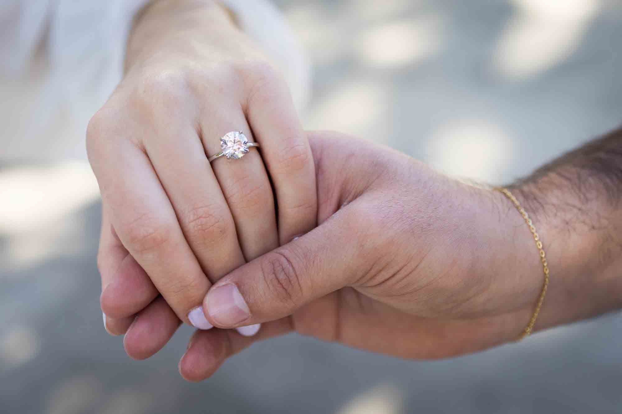 Close up of man holding woman's hand showing engagement ring