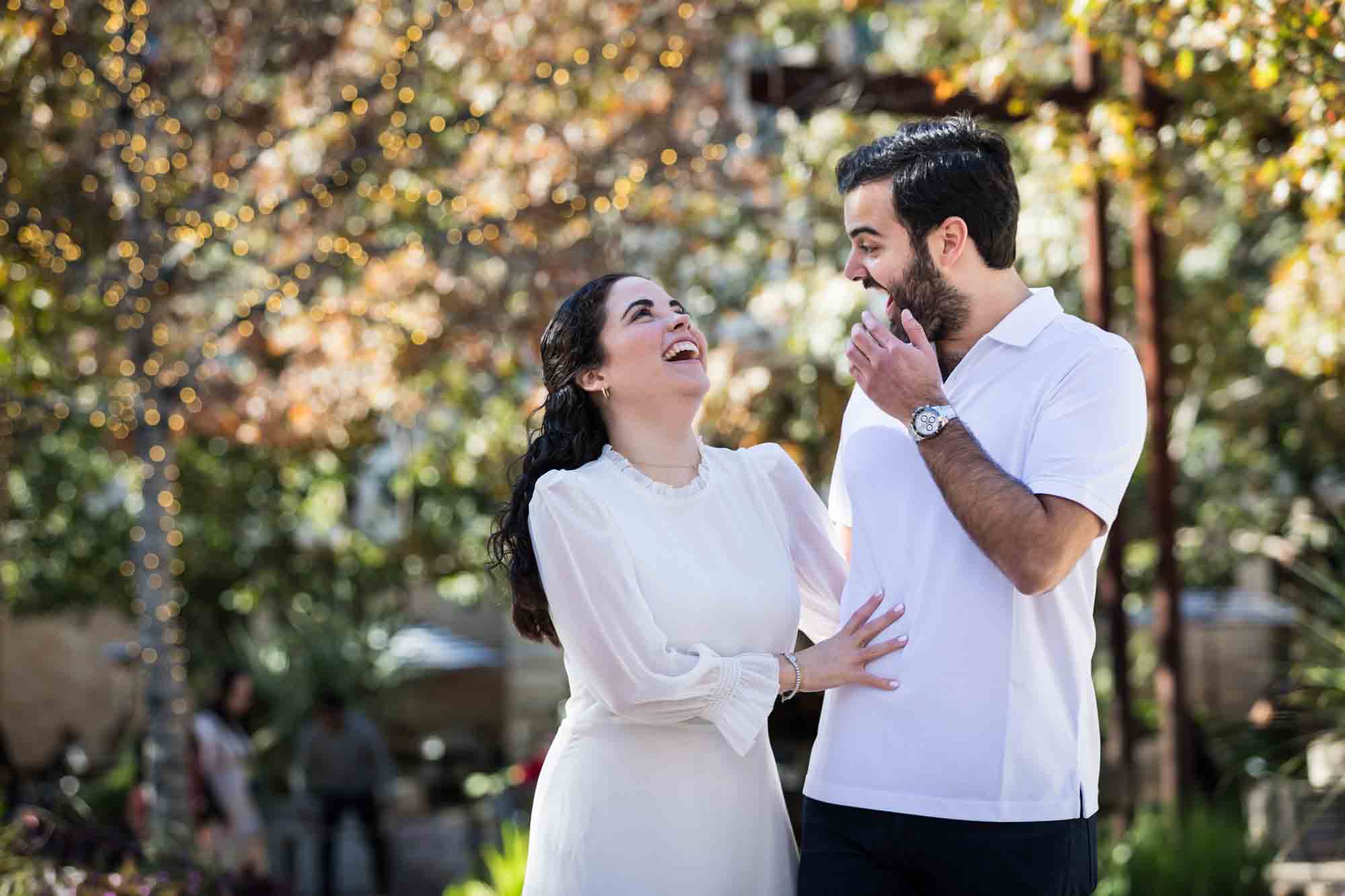 Couple laughing while walking in front of trees during a Pearl engagement portrait session