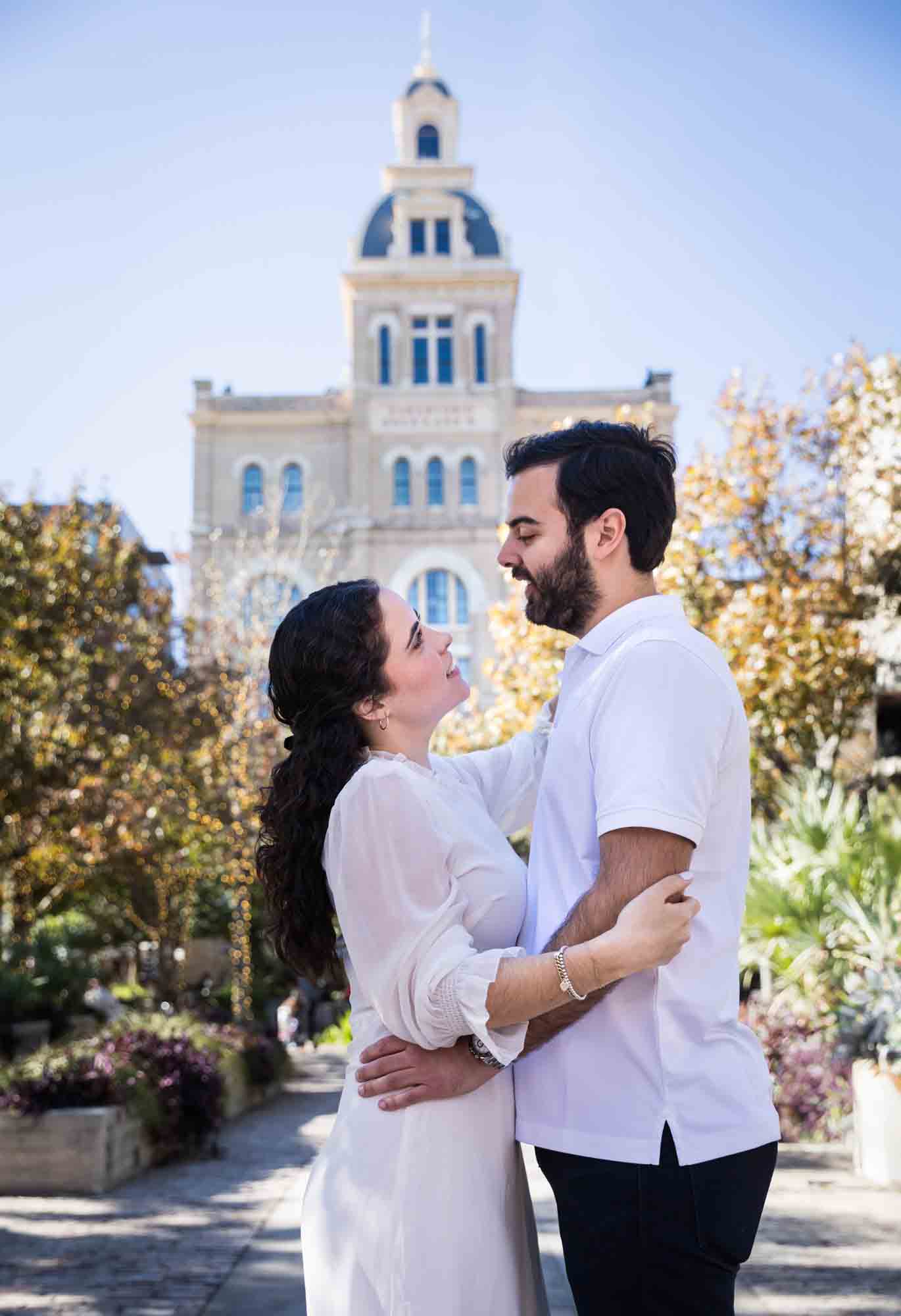 Couple embracing in front of Pearl Brewery Building during a Pearl engagement portrait session