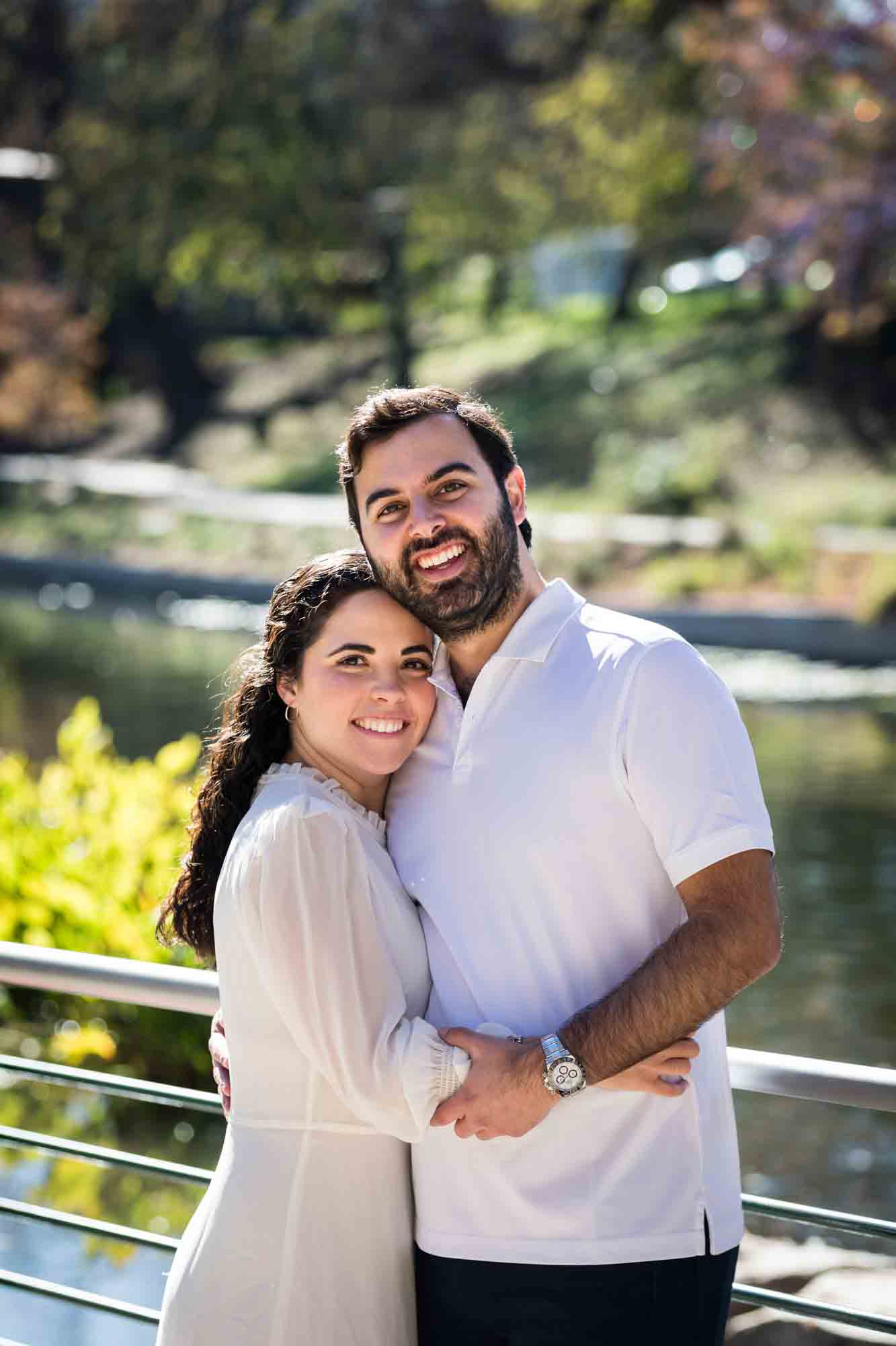 Couple hugging in front of Riverwalk during a Pearl engagement portrait session