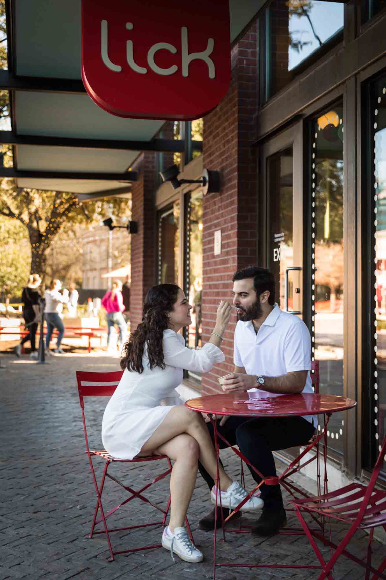 Couple eating ice cream at red table during a Pearl engagement portrait session