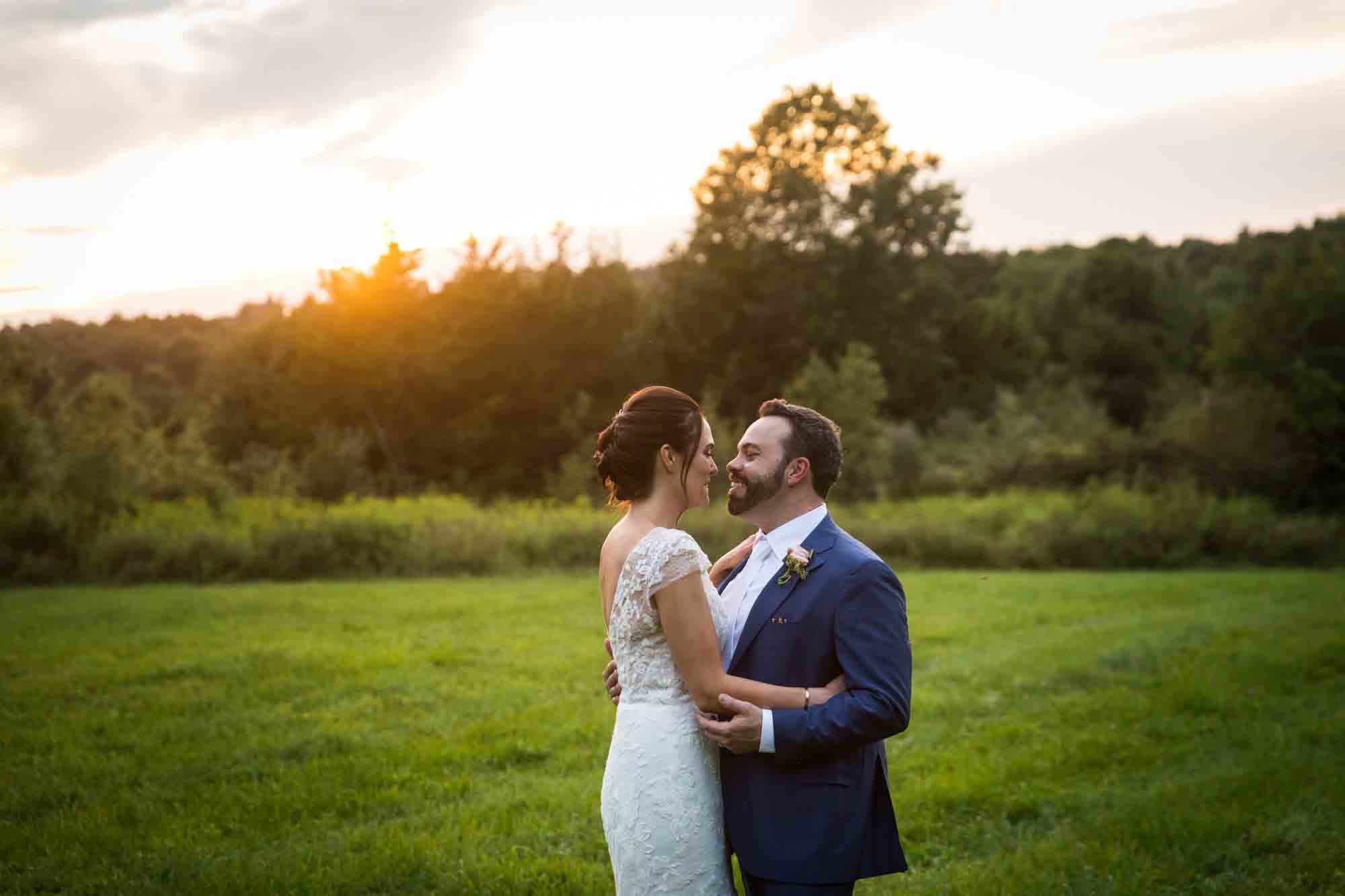Bride and groom hugging on grass with sunset in background for an article on how to find a San Antonio wedding photographer
