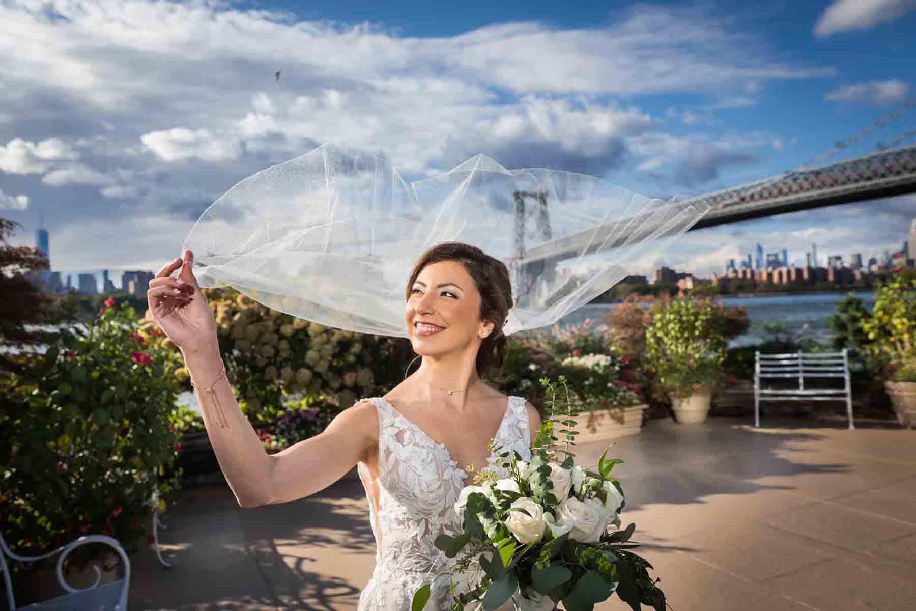 Bride holding veil that is blowing in the wind