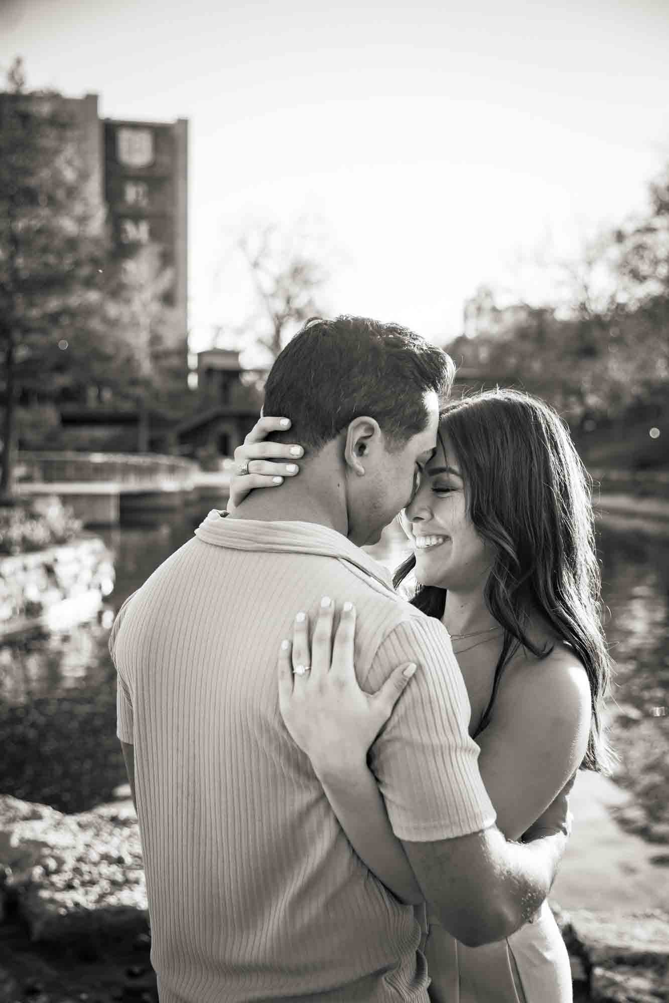 Couple hugging with Riverwalk in the background for an article on how to propose at the Pearl
