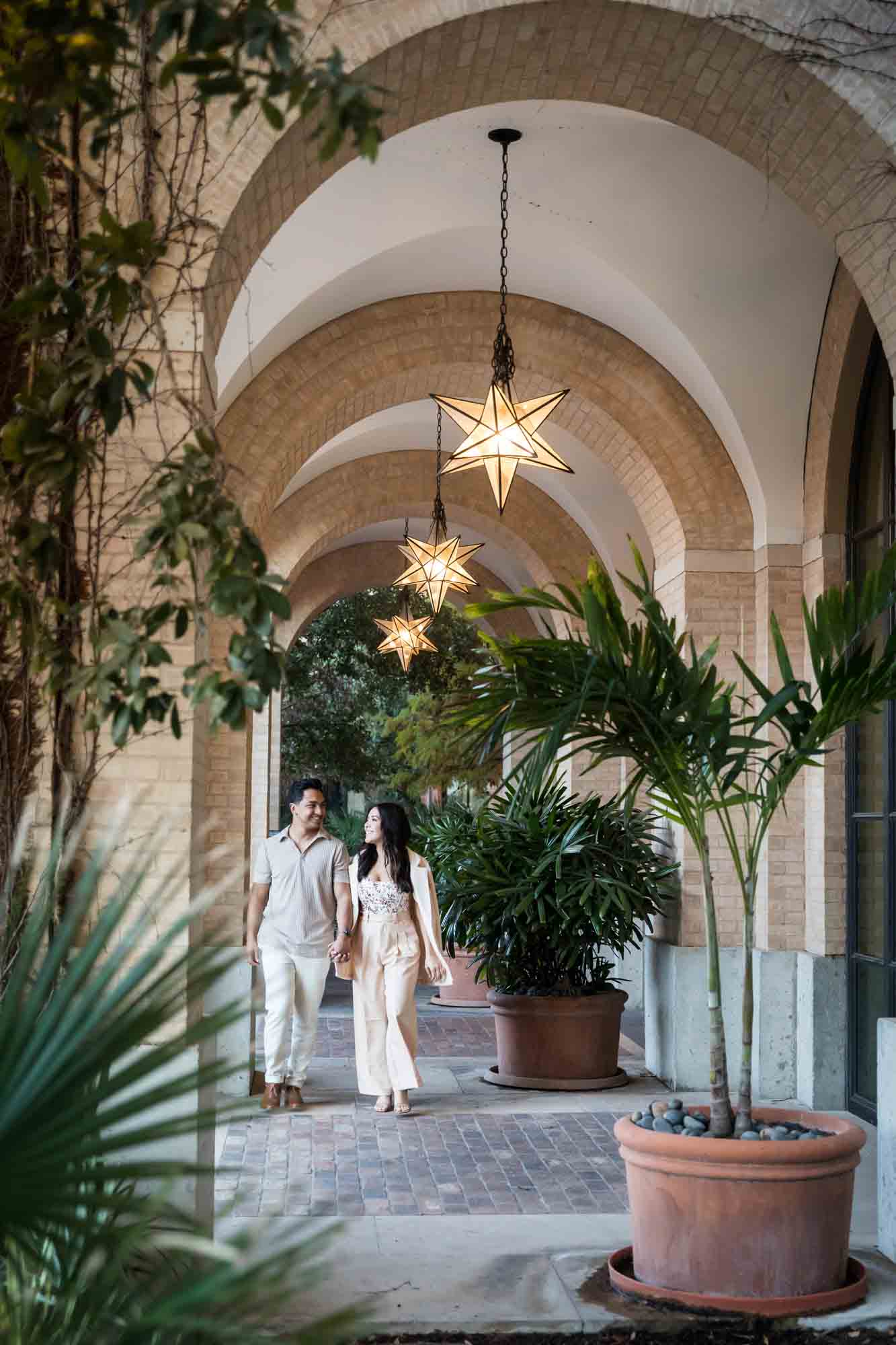 Couple walking under star-shaped lights surrounded by plants for an article on how to propose at the Pearl