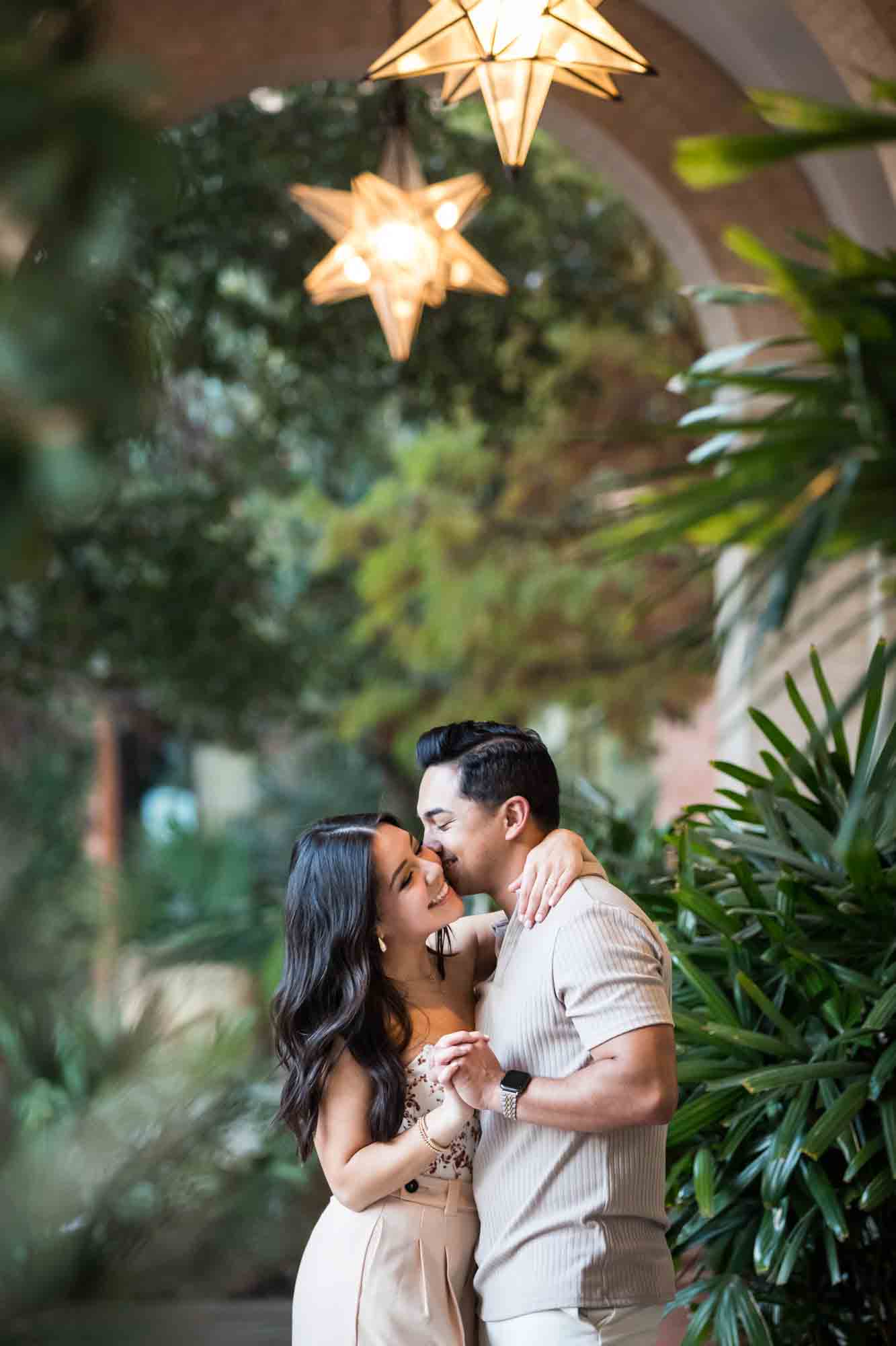 Couple dancing under star-shaped lights surrounded by plants for an article on how to propose at the Pearl