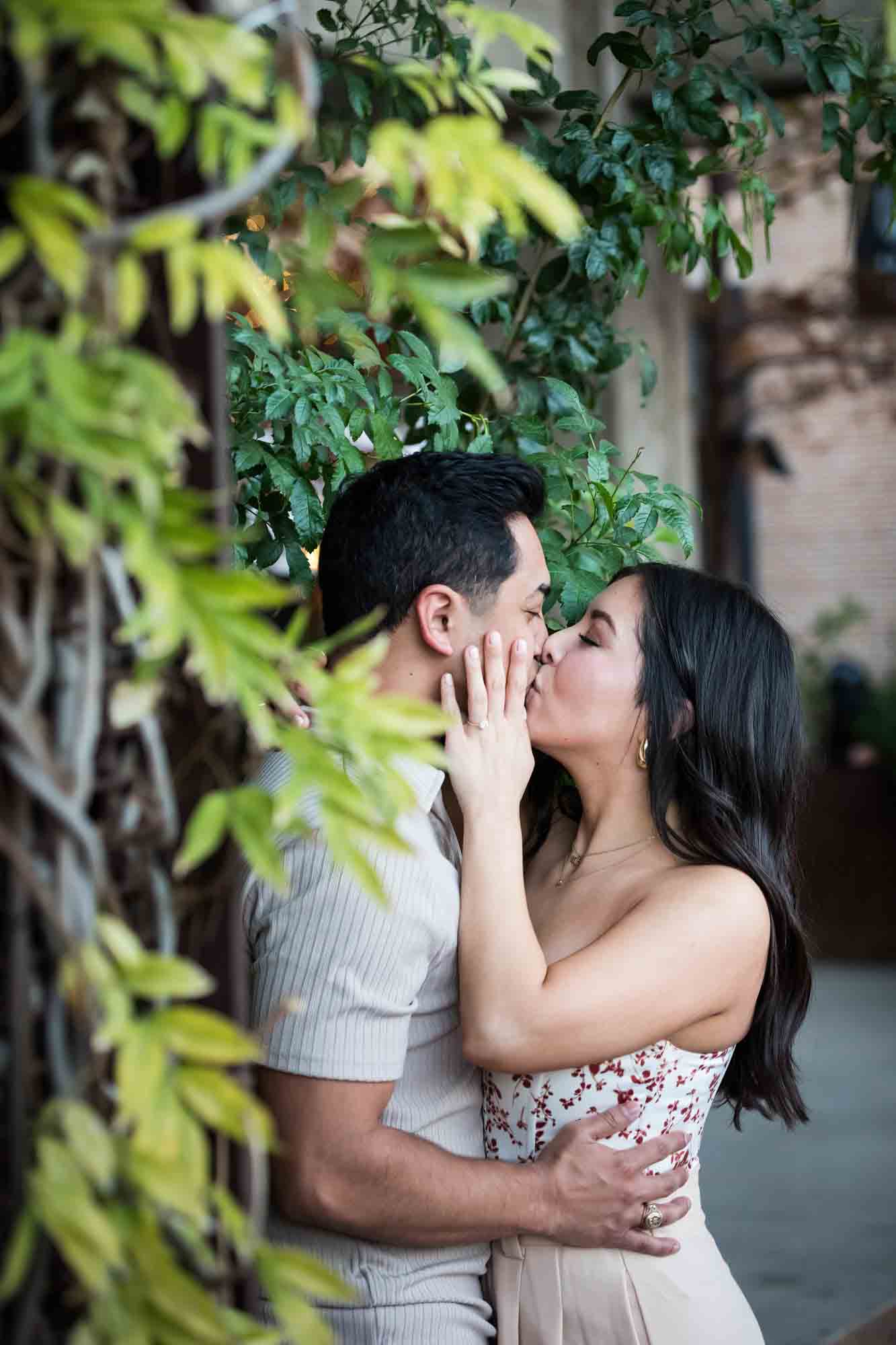 Woman kissing man surrounded by wall with vines for an article on how to propose at the Pearl