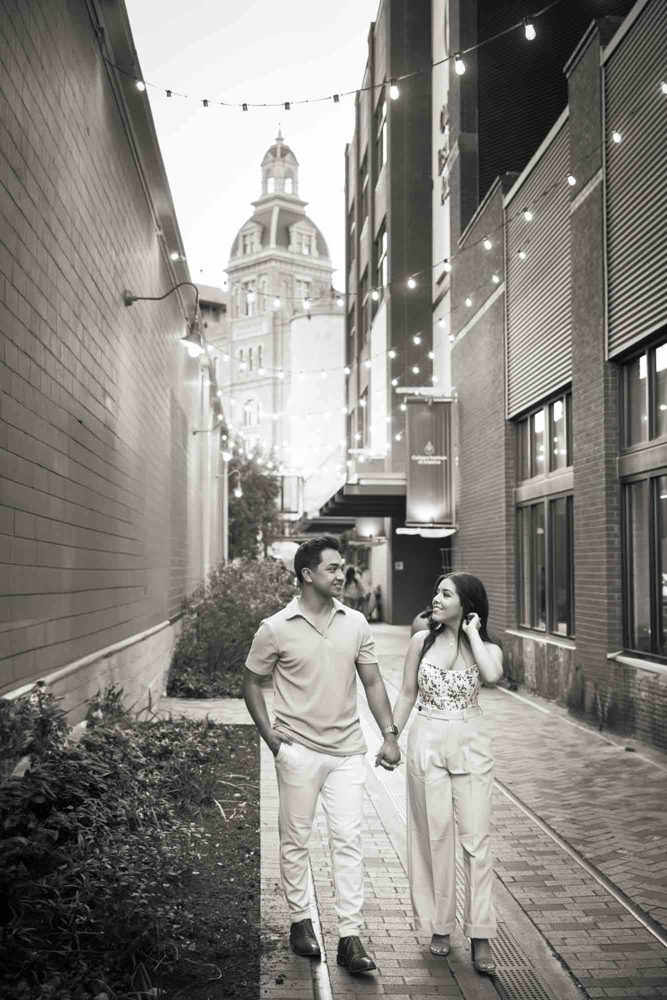 Couple walking in alleyway lit by fairy lights for an article on how to propose at the Pearl