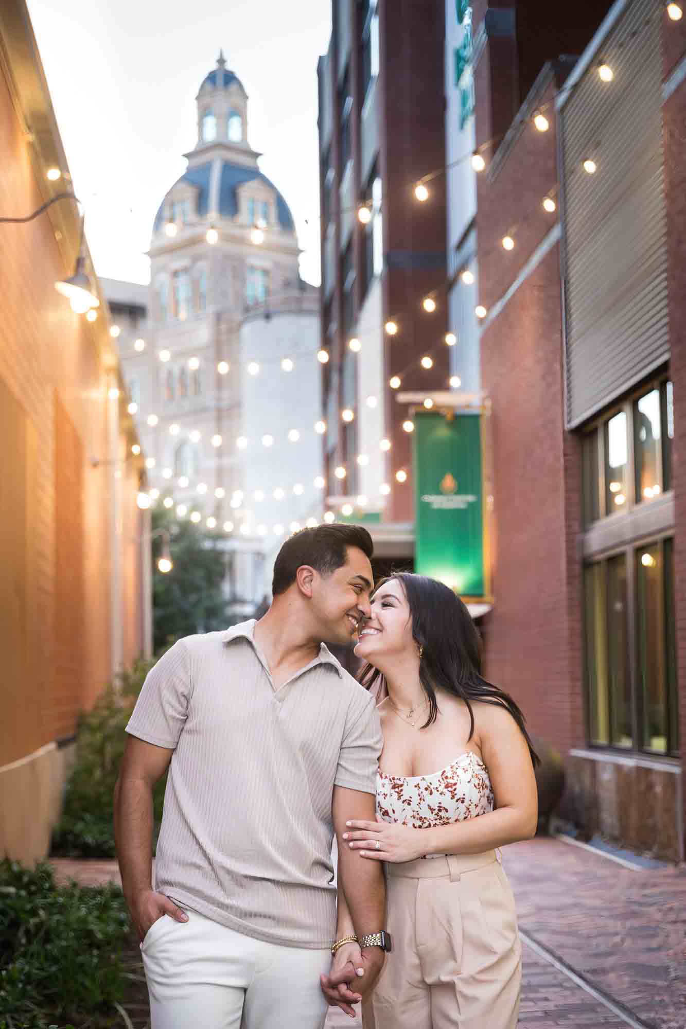 Couple hugging in alleyway lit by fairy lights for an article on how to propose at the Pearl