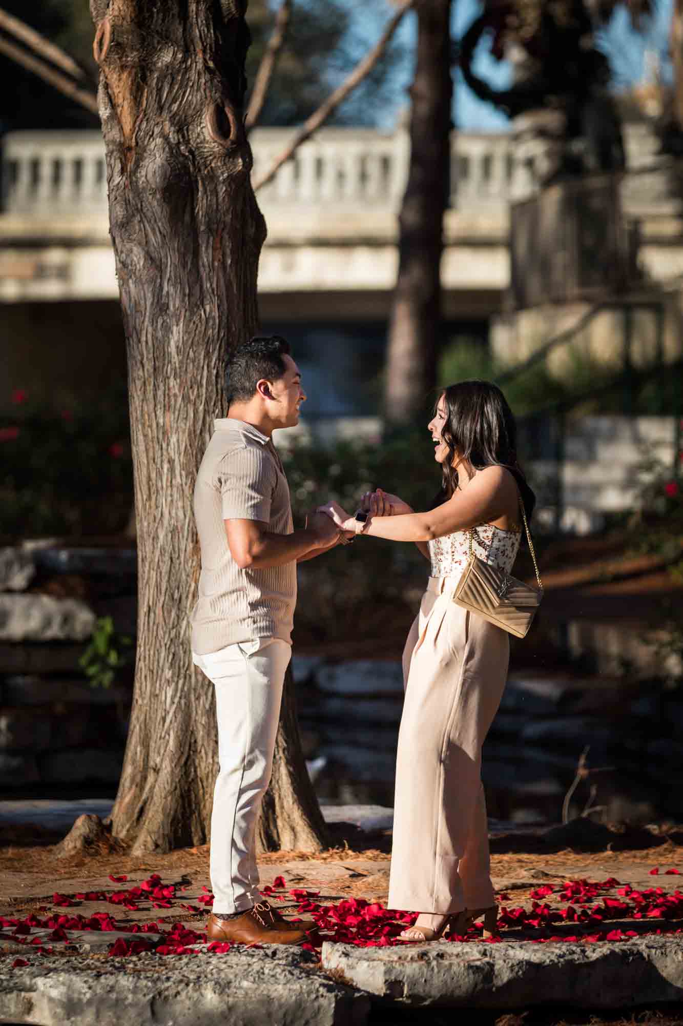 Man holding woman's hands on island before surprise proposal at the Pearl in San Antonio
