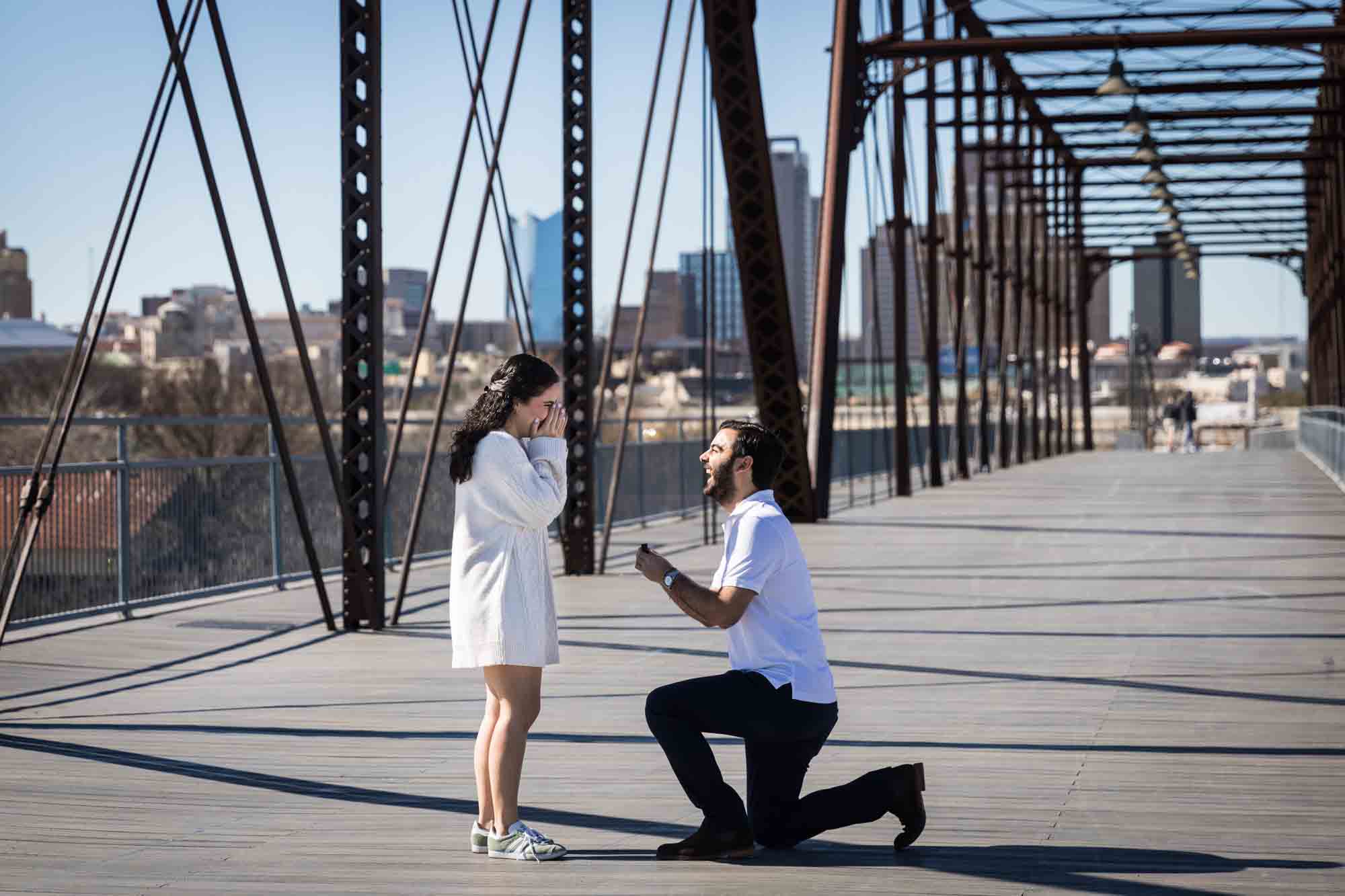 Man on bended knee proposing to woman on Hays Street Bridge by San Antonio photographer, Kelly Williams