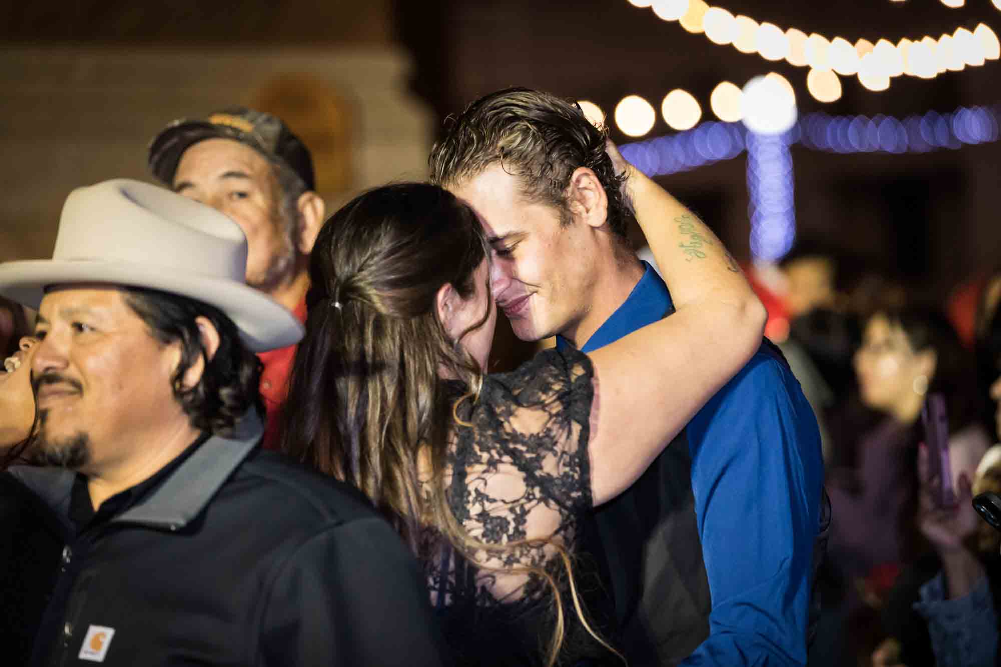 Woman wearing black dress dancing with man wearing blue shirt in crowd at night for an article on the Bexar county mass wedding event