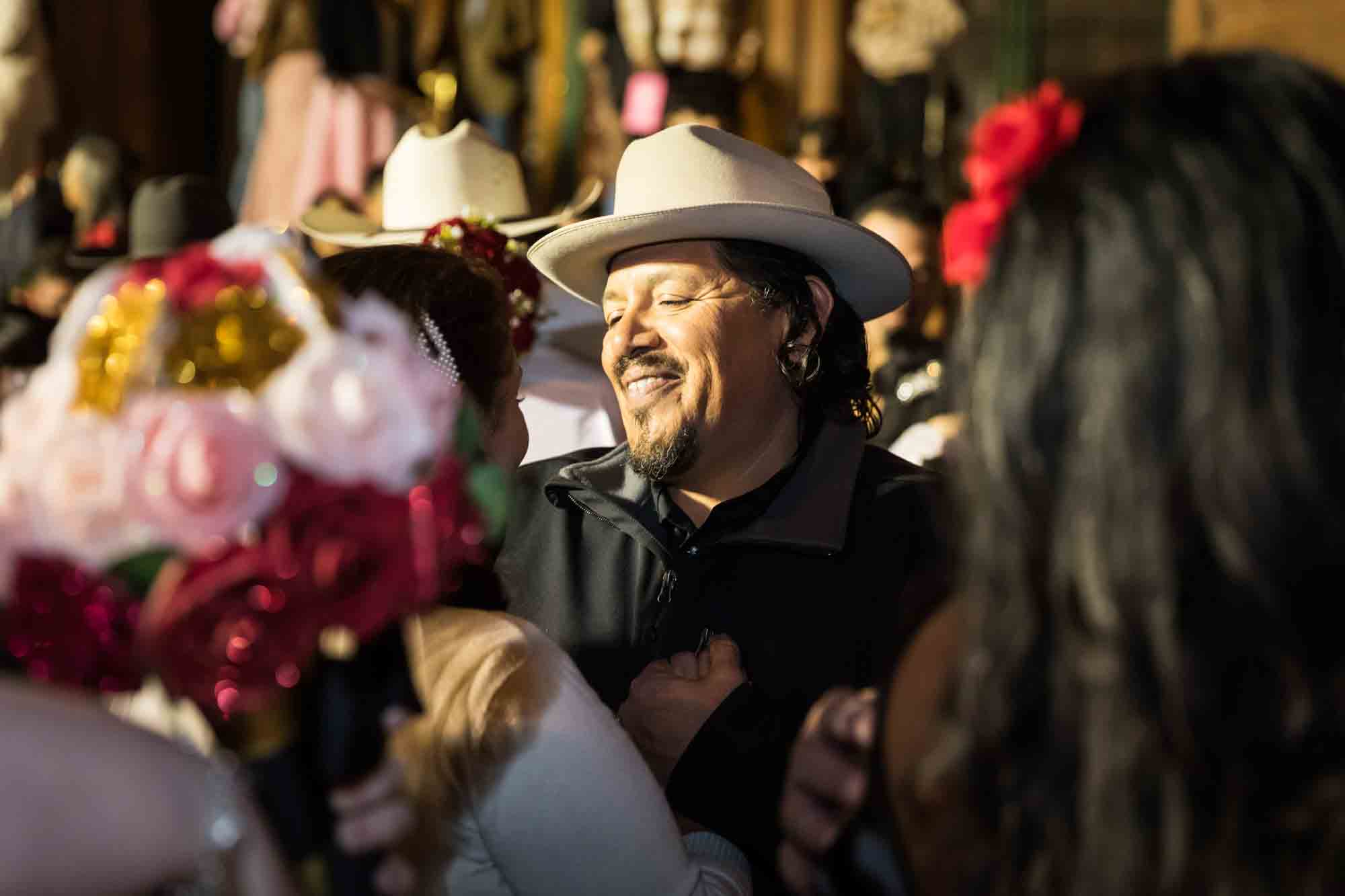 Man wearing white cowboy hat looking at bride for an article on the Bexar county mass wedding event