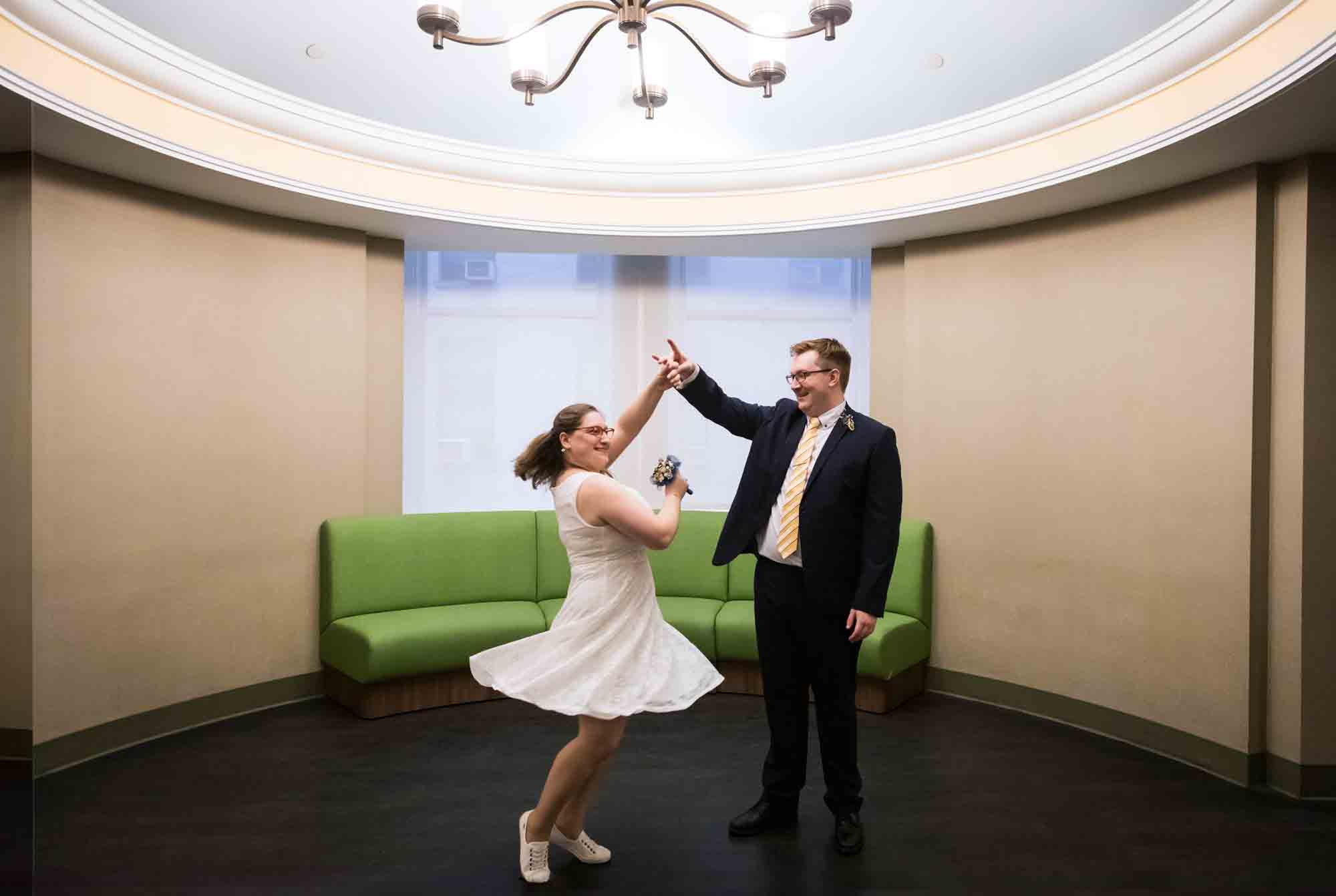 Bride and groom dancing under chandelier in front of green couch for an article on how to get a marriage license in San Antonio
