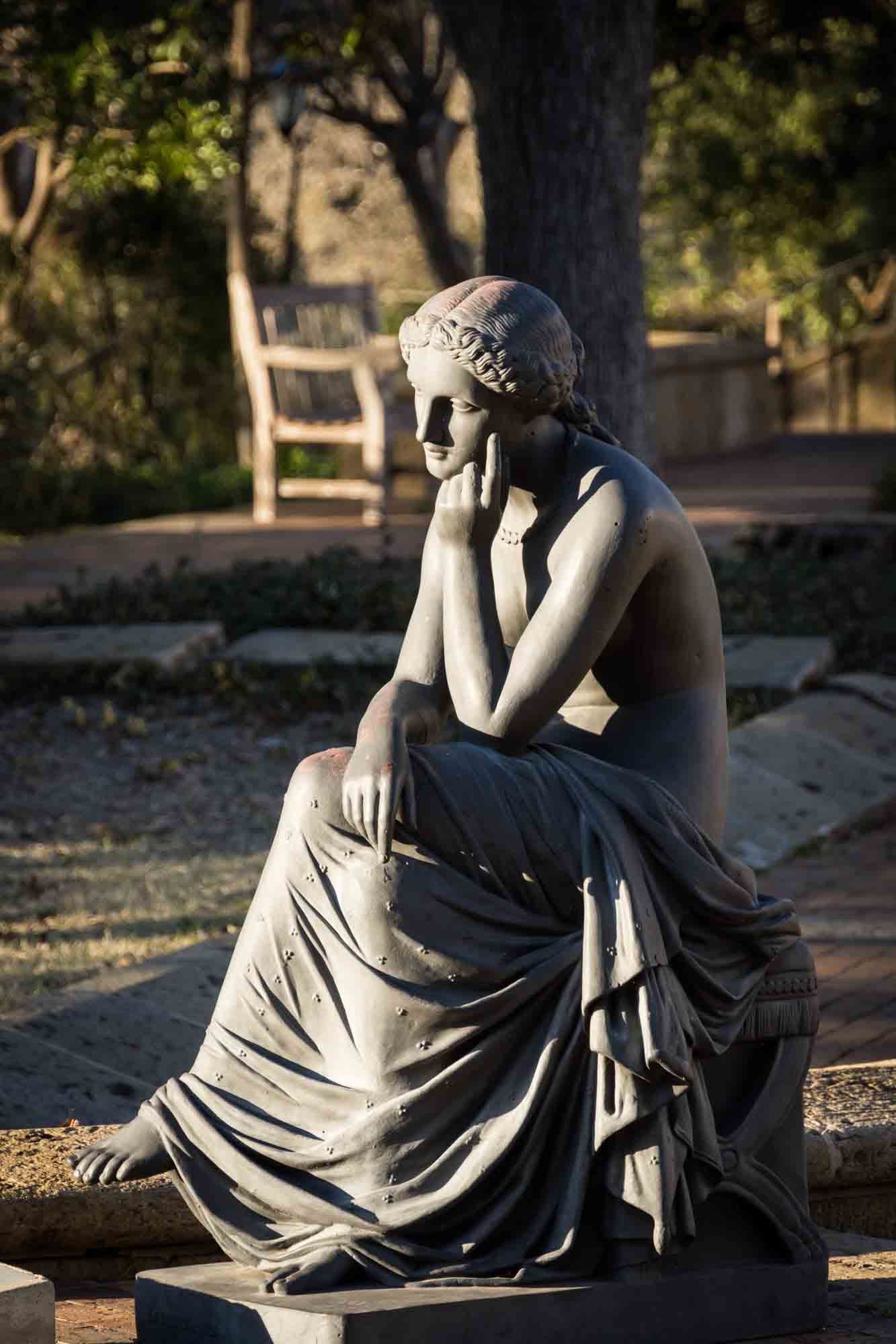 Grey sculpture of woman sitting with arms on knees for an article on how to take photos at the McNay Art Museum