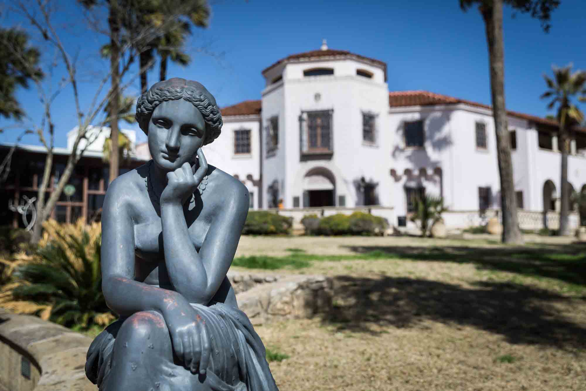 Main house of McNay Art Museum with grey sculpture of woman in front for an article on how to take photos at the McNay Art Museum