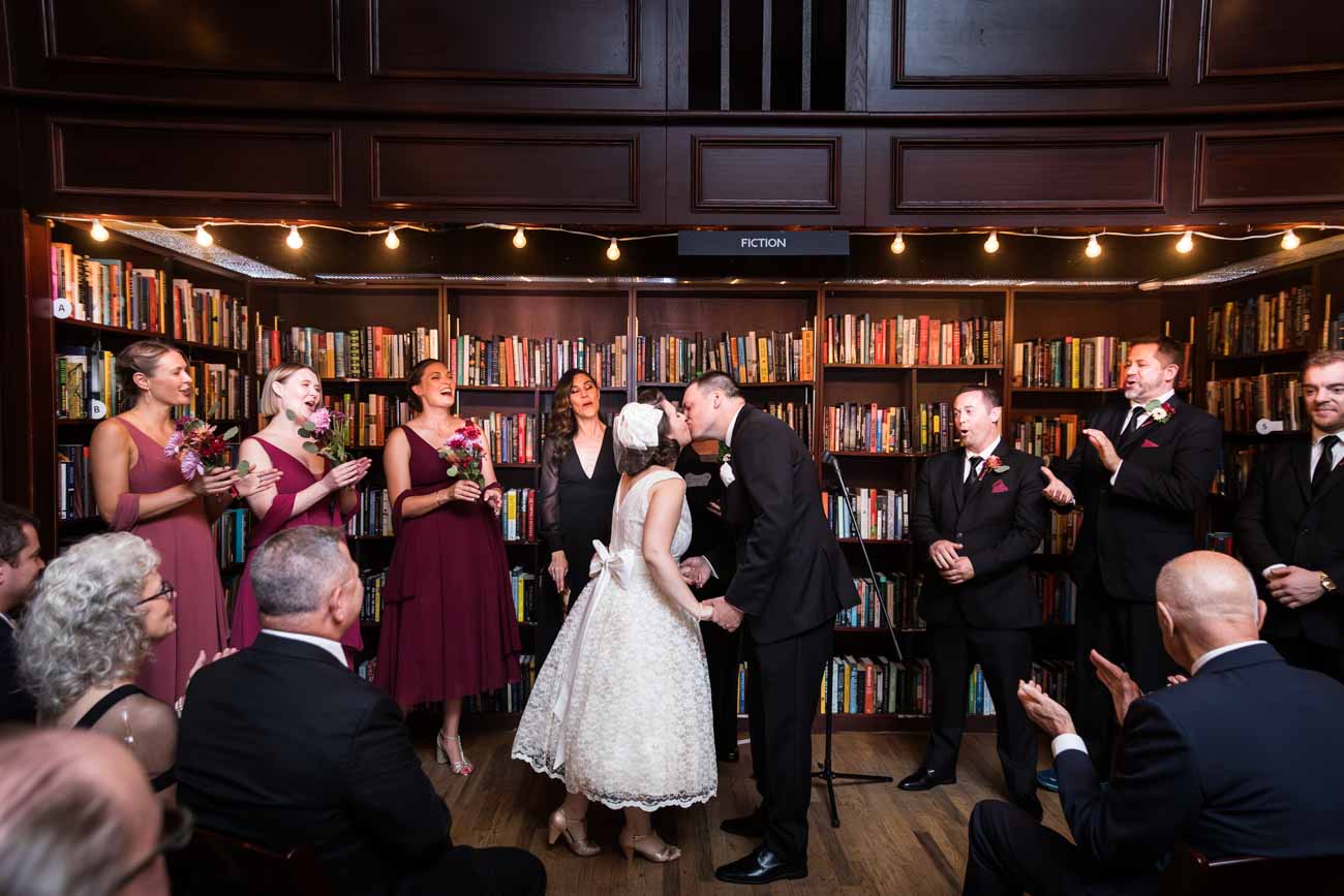 Bride and groom kissing during ceremony in bookstore for an article on how to become a wedding officiant in San Antonio