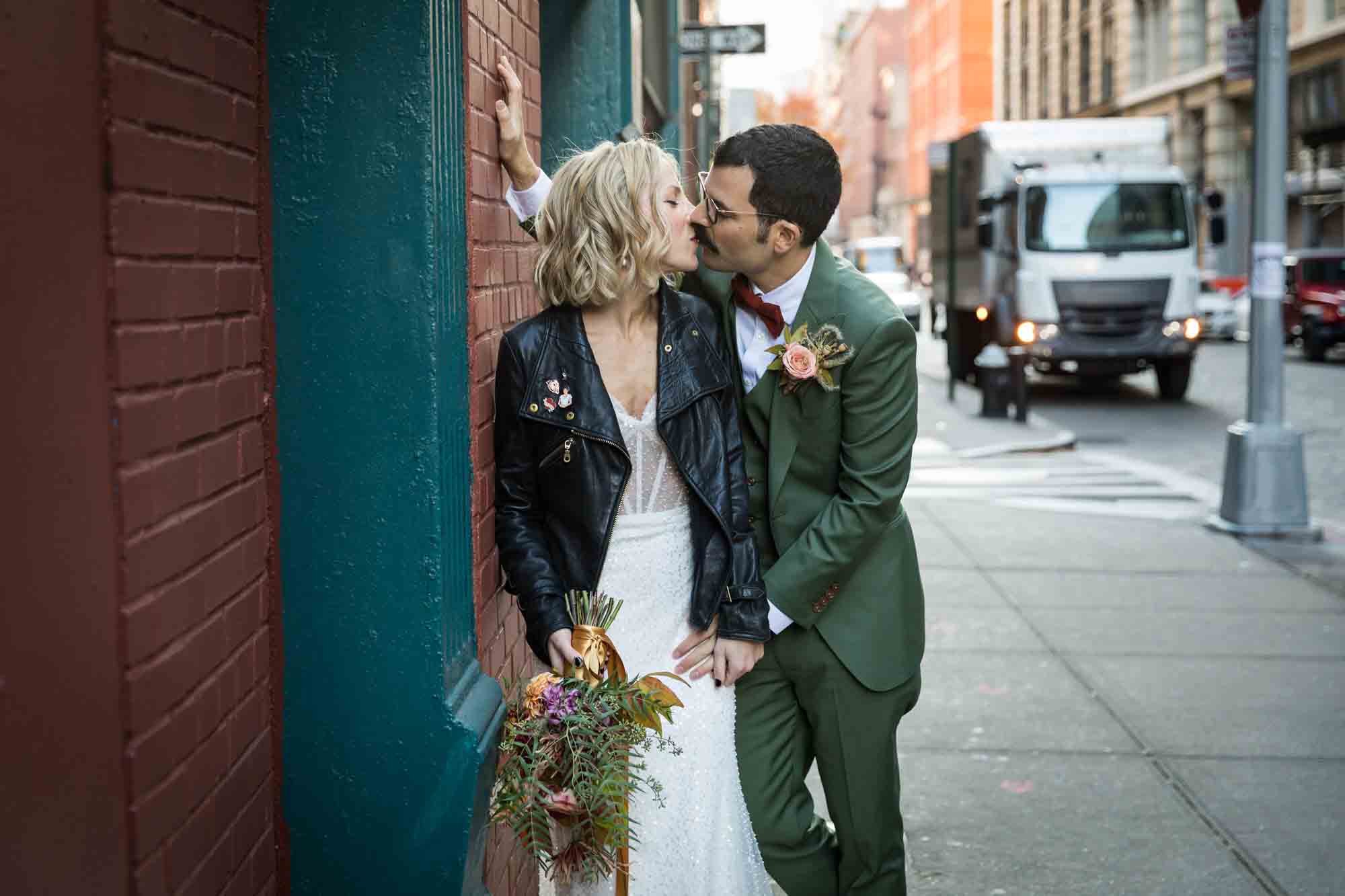 Bride and groom kissing on sidewalk for an article on should you give your wedding photographer a shot list