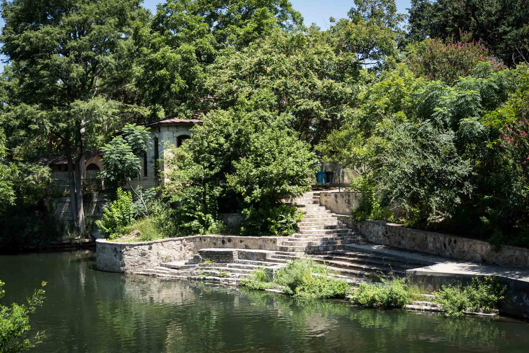 Stone building with steps leading down to river in Brackenridge Park for an article on the best San Antonio parks for family portraits