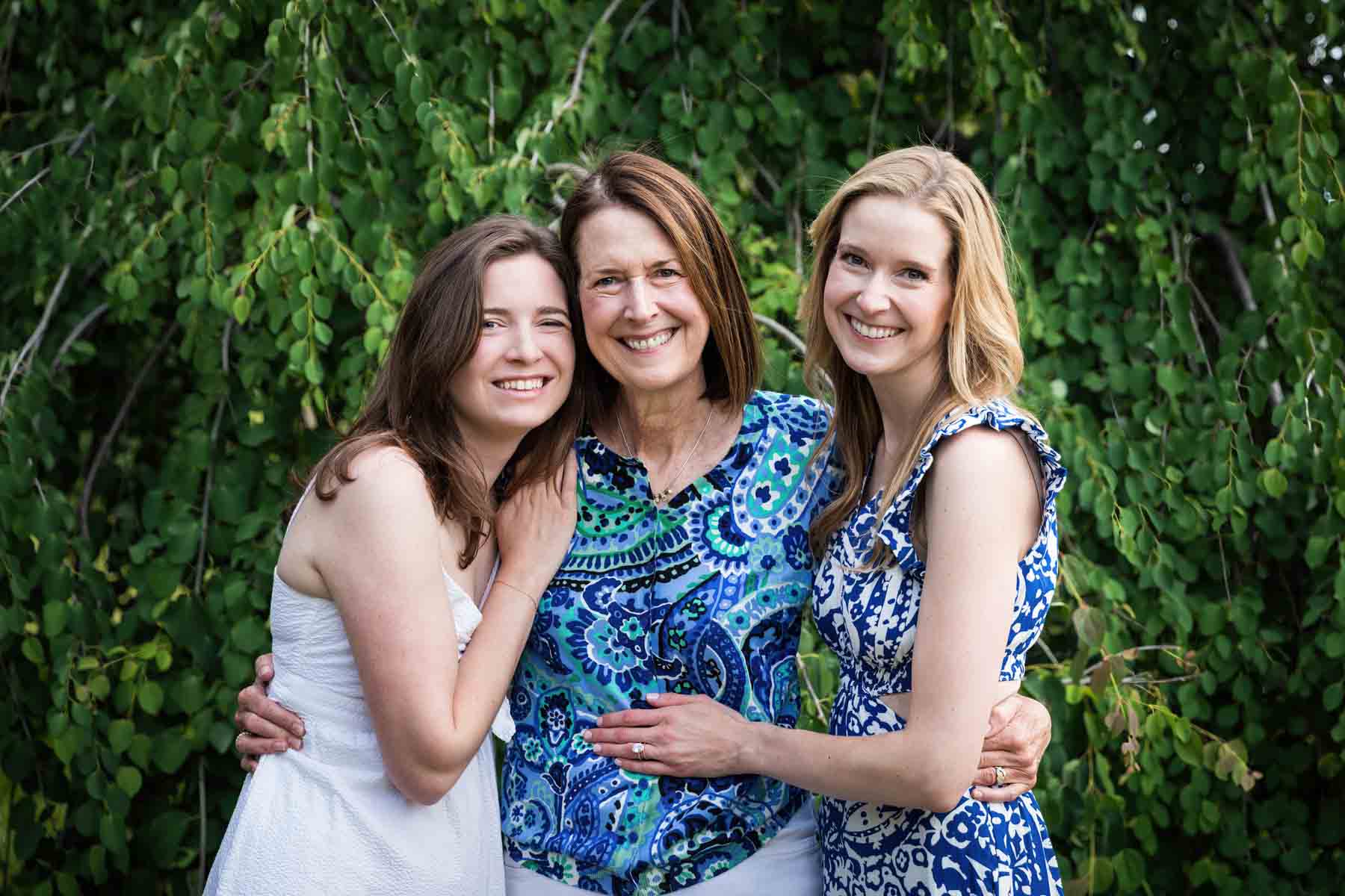 Mother and two daughters hugging in front of trees for an article on the best San Antonio parks for family portraits