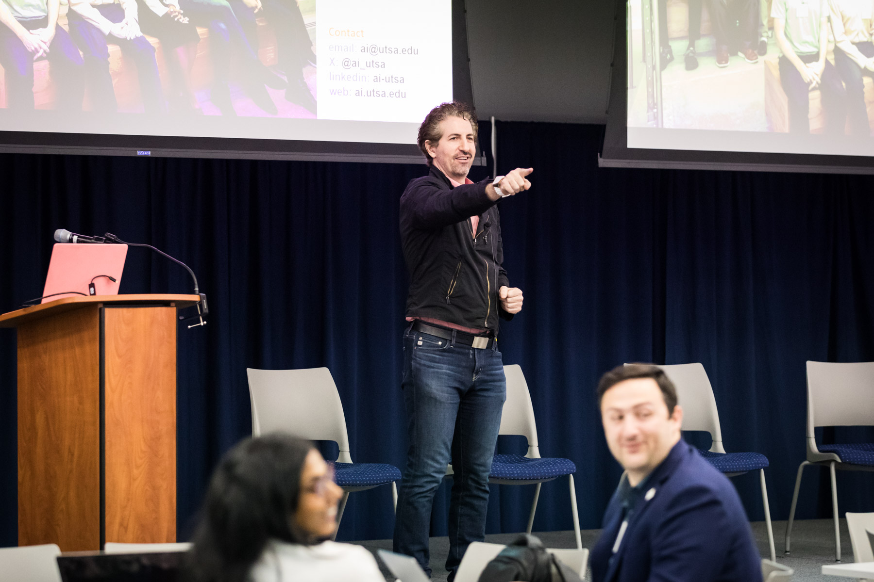 Male speaker on stage pointing to audience during a UTSA conference for an article on corporate event photo tips