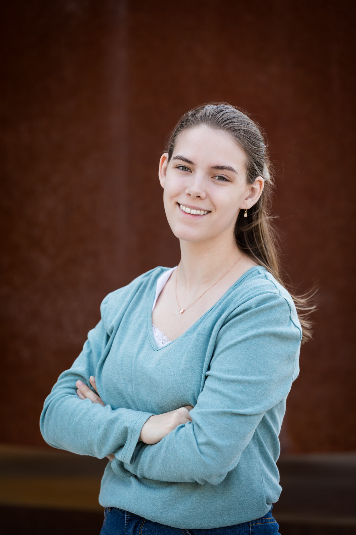 Headshot of woman wearing blue shirt in front of rust-colored background for an article on corporate event photo tips