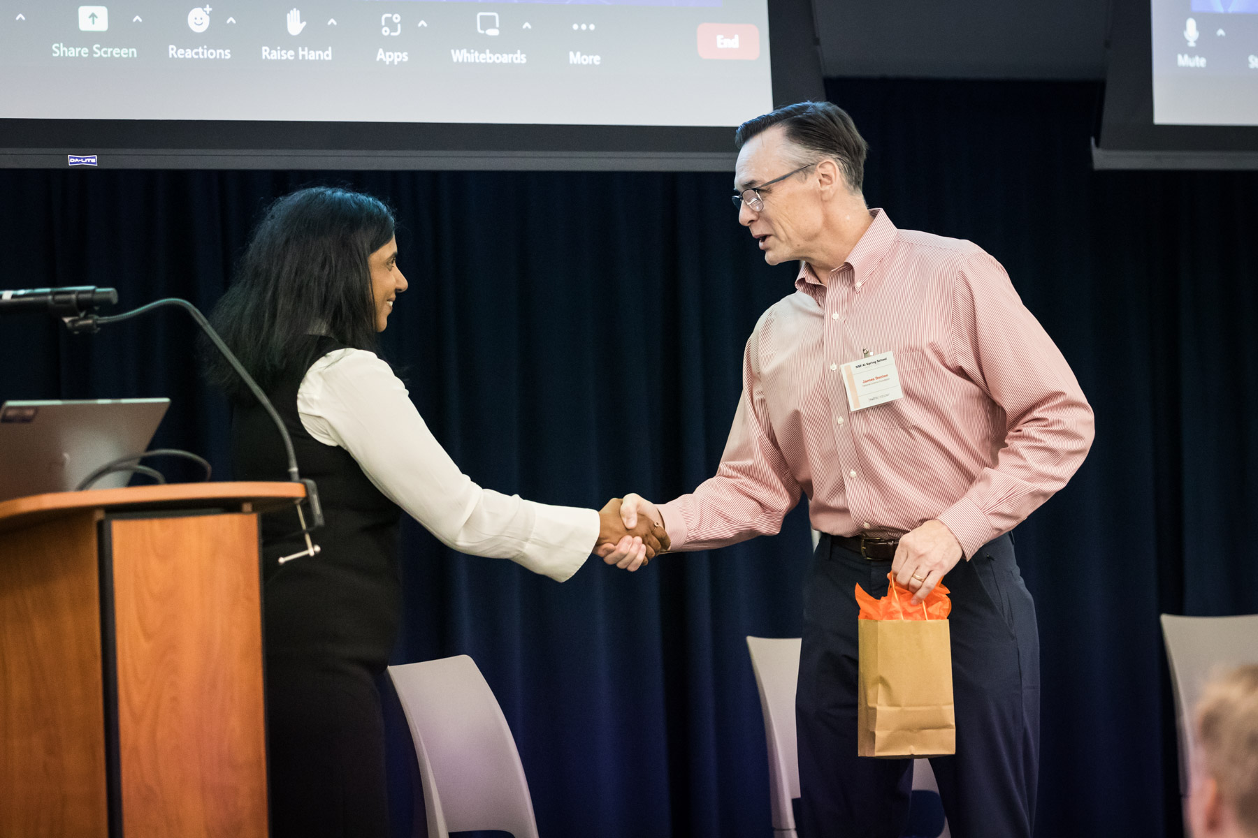 Man and woman shaking hands on stage during UTSA conference for an article on corporate event photo tips