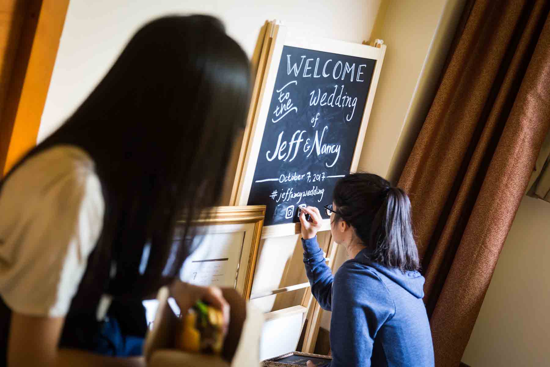 Woman writing on chalkboard in hotel room for an article on the best wedding jobs for family and friends