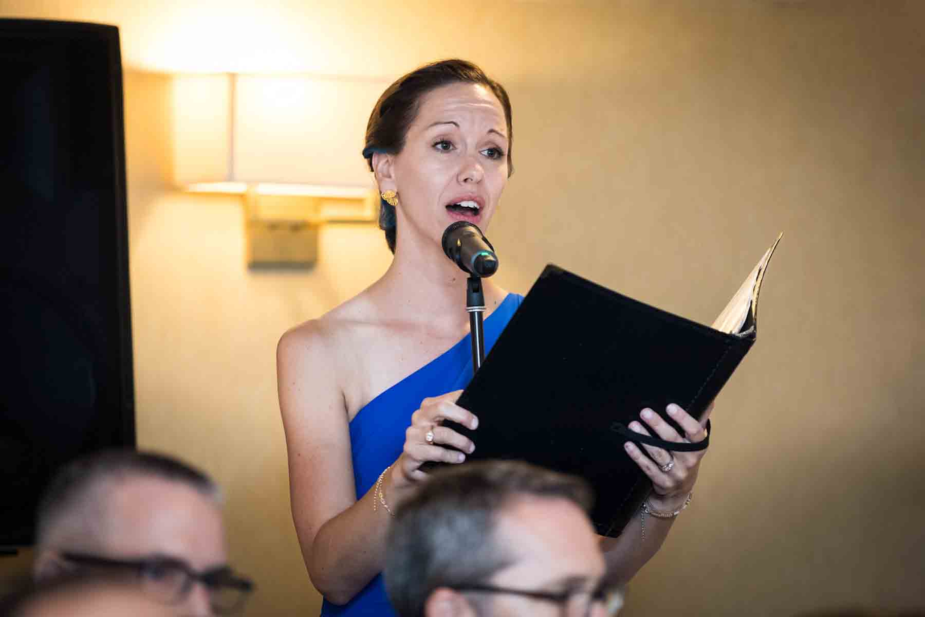 Woman holding notebook and signing into microphone for an article on the best wedding jobs for family and friends