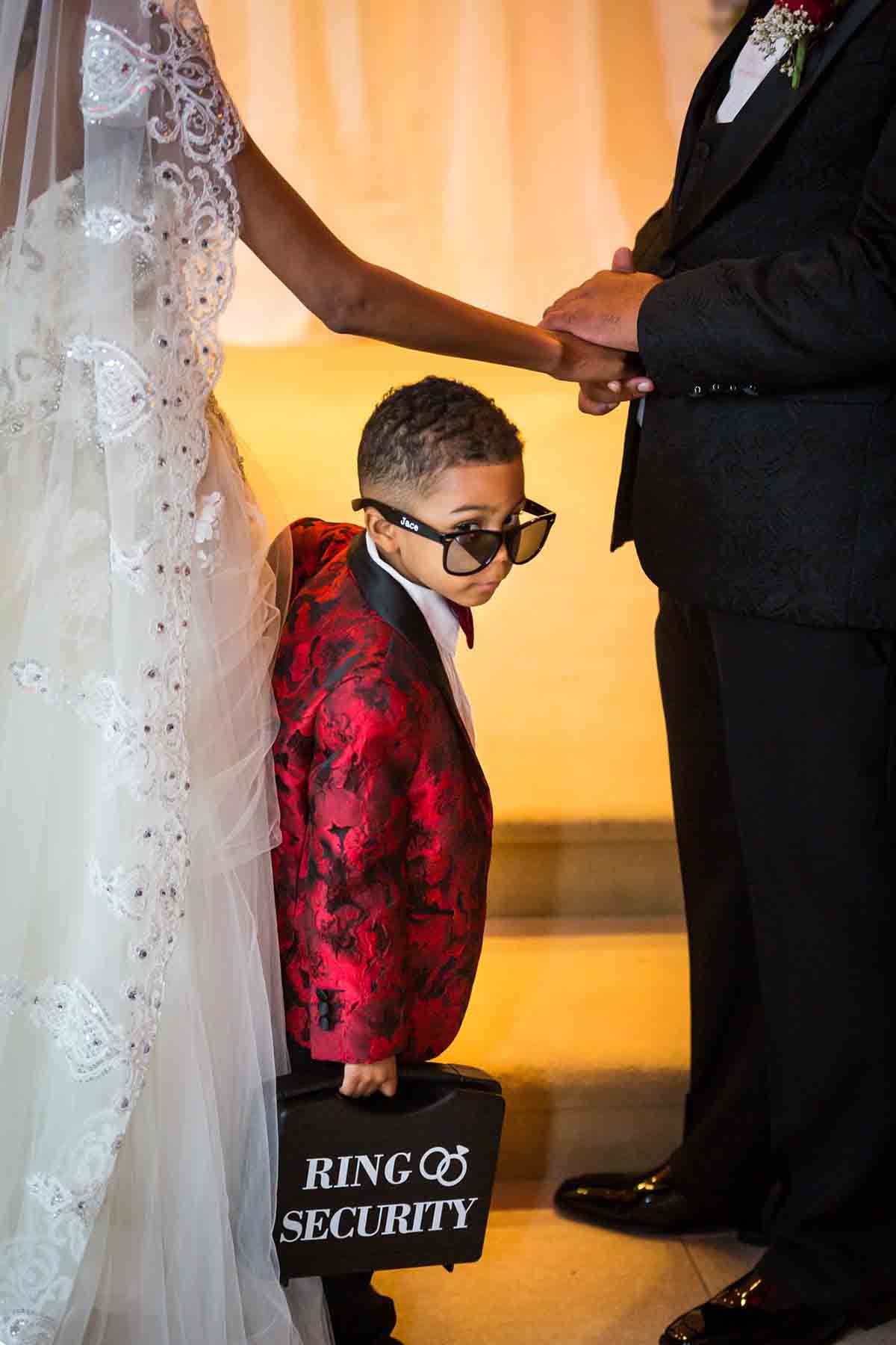Little ring bearer wearing red jacket and sunglasses for an article on the best wedding jobs for family and friends