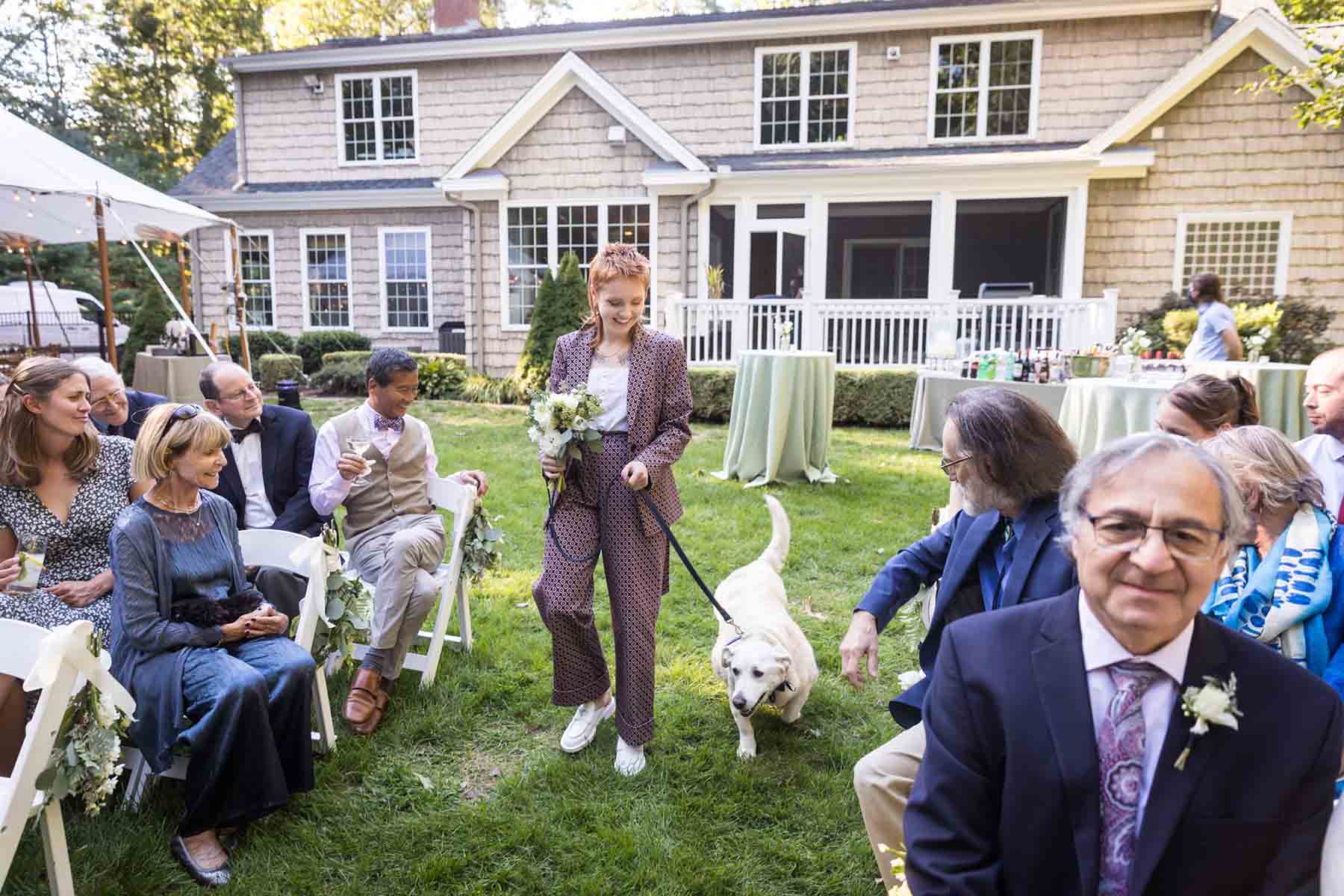 Woman leading dog on leash down aisle at wedding for an article on the best wedding jobs for family and friends