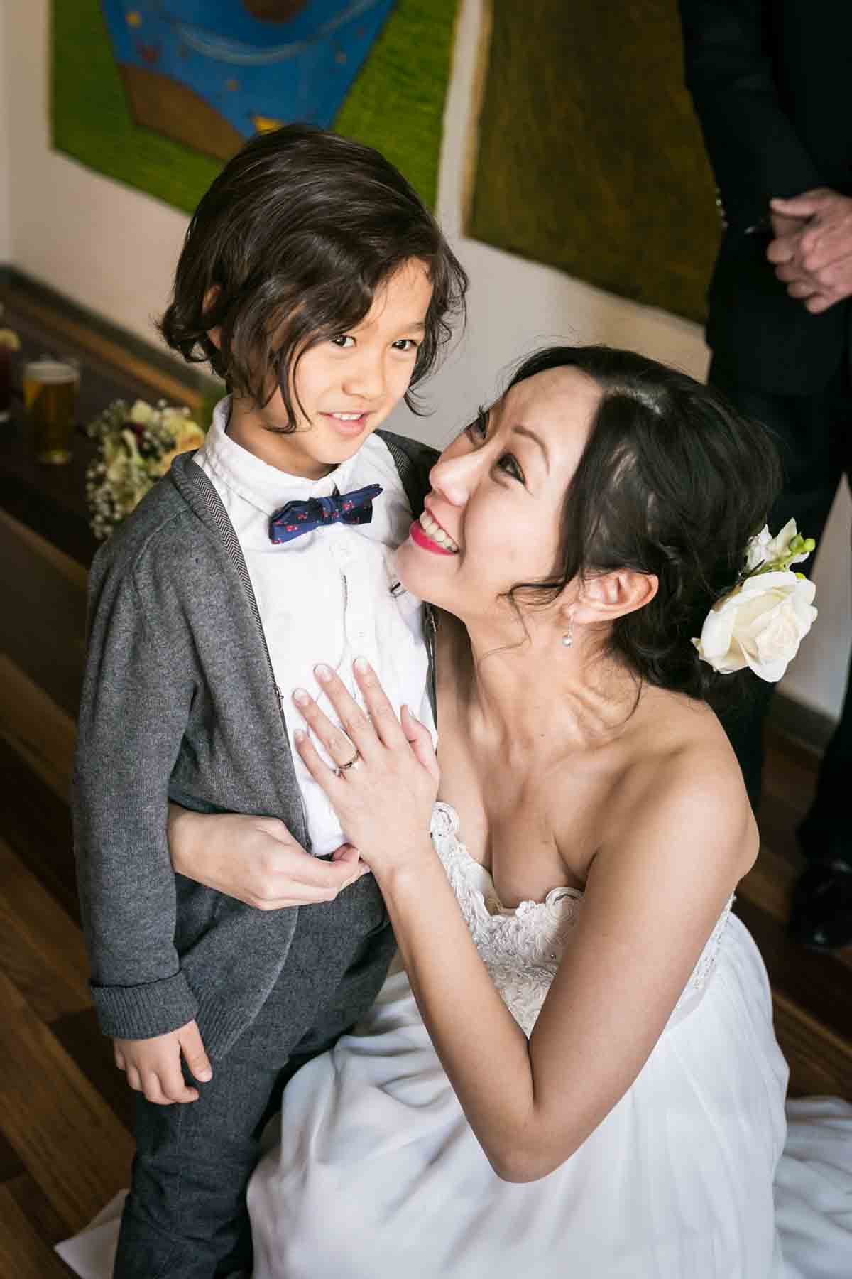 Bride hugging little boy wearing bow tie for an article on the best wedding jobs for family and friends