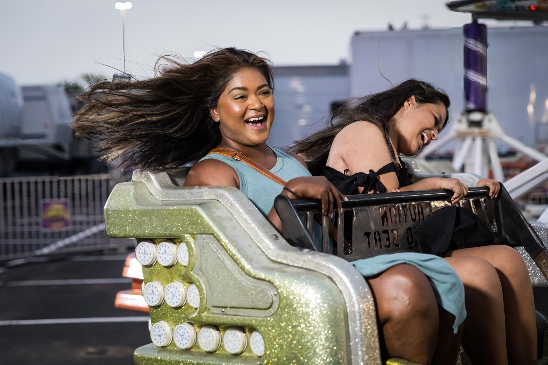 Two girls with hair flying on carnival ride for an article on the best Fiesta photos
