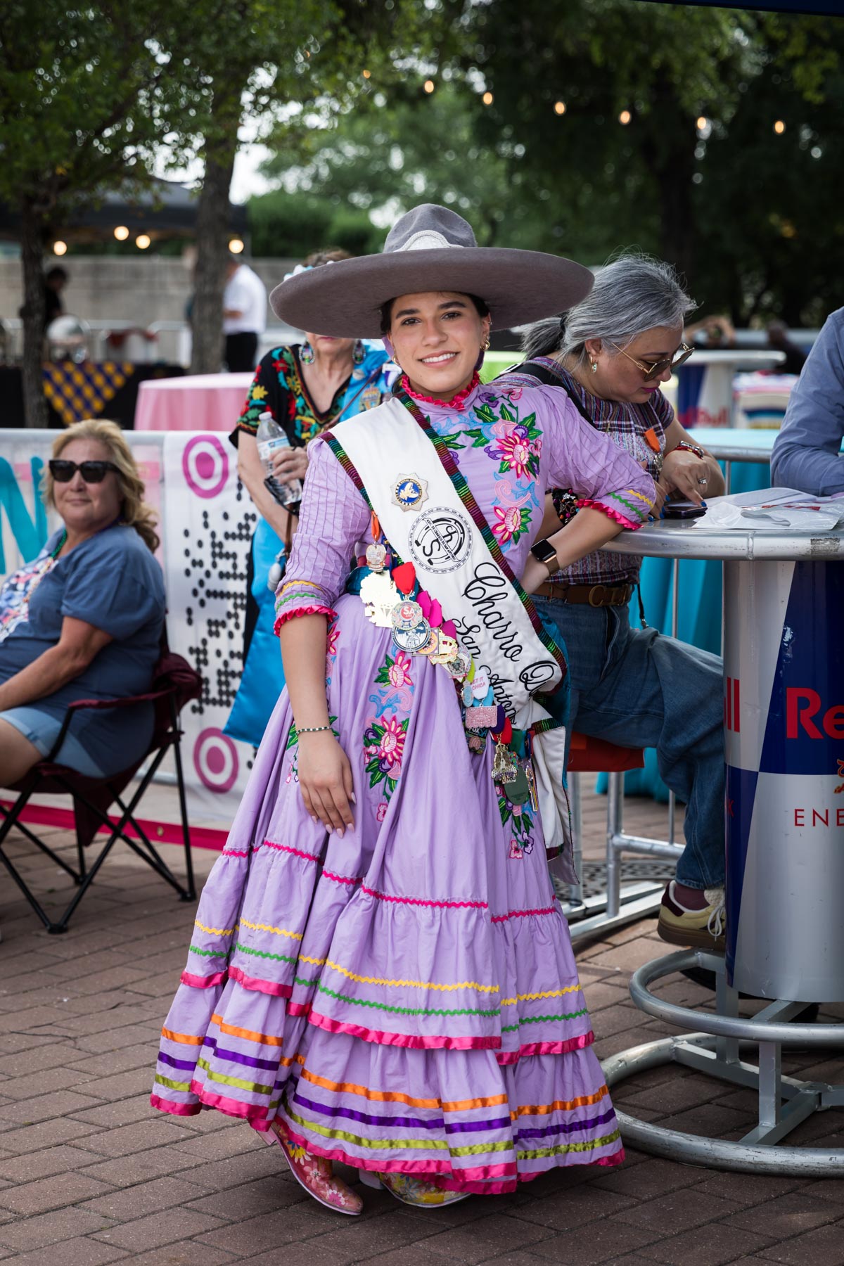 Girl wearing traditional purple dress, sash, and traditional cowboy hat for an article on the best Fiesta photos
