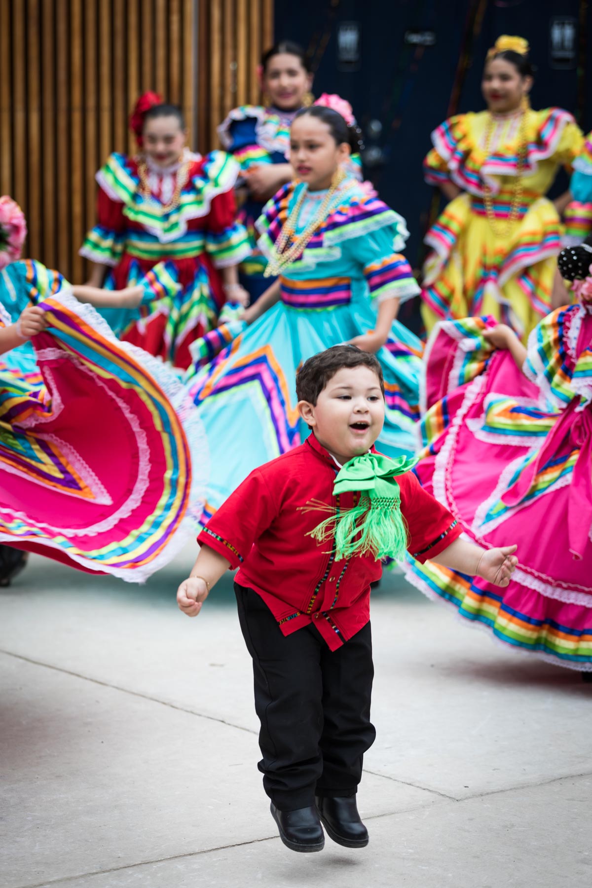 Little boy jumping in front of colorful, traditional dancers at Rey Fido event for an article on the best Fiesta photos