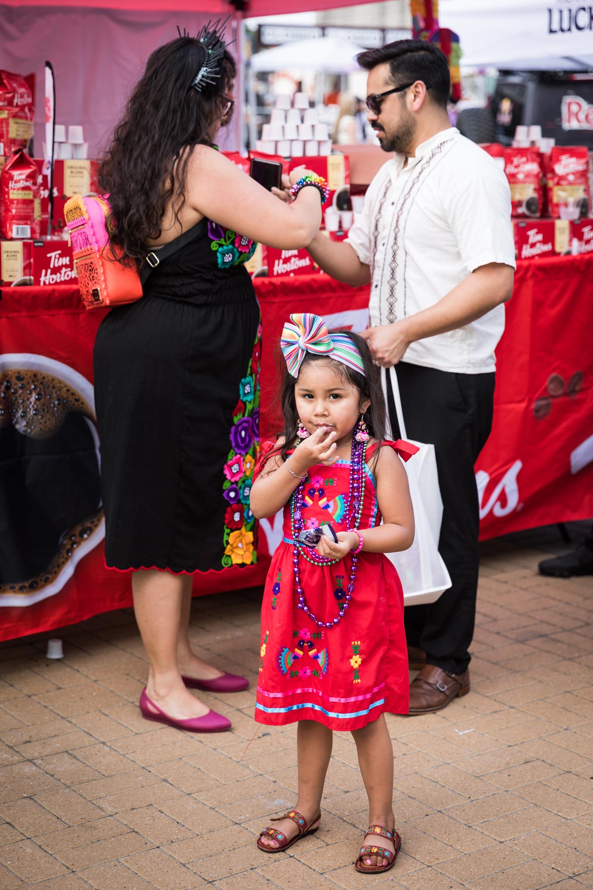 Little girl wearing red dress and putting food in mouth for an article on the best Fiesta photos