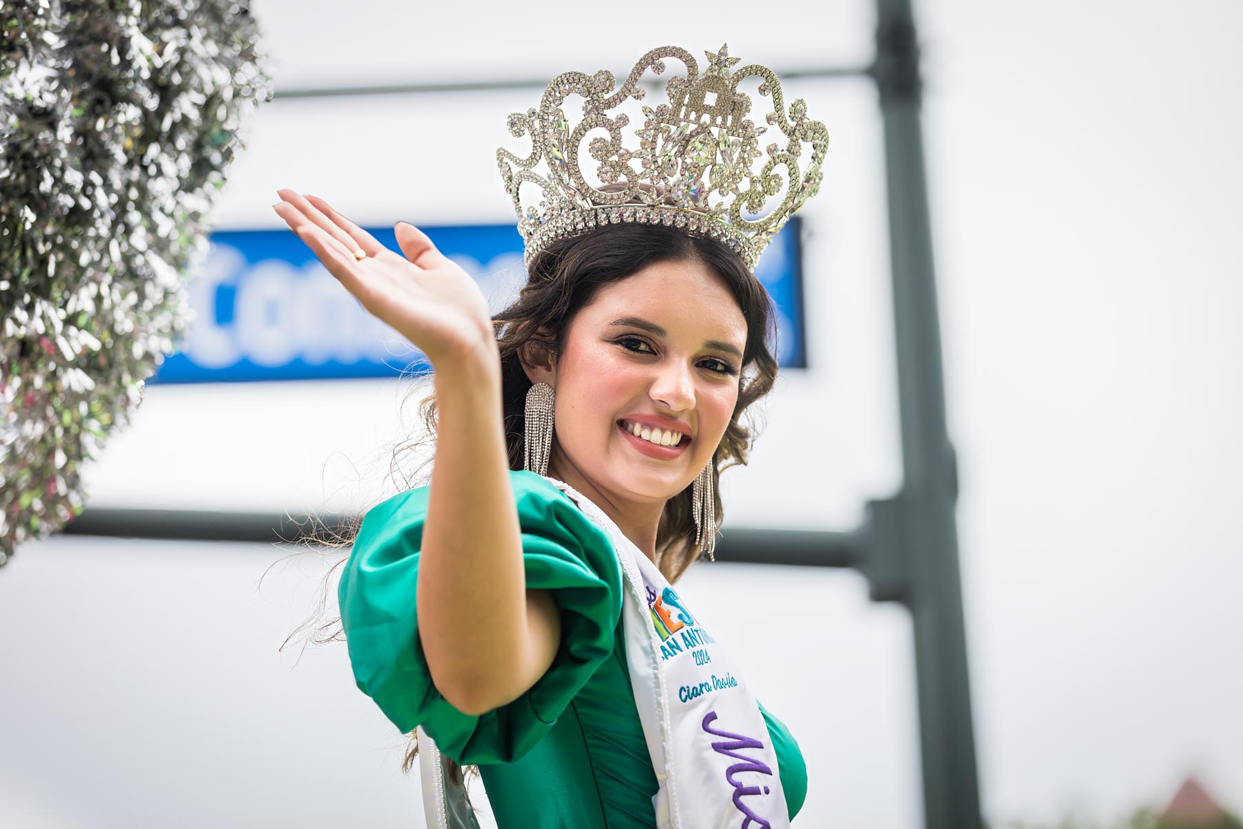 Miss Fiesta wearing green dress and large tiara waving for an article on the best Fiesta photos