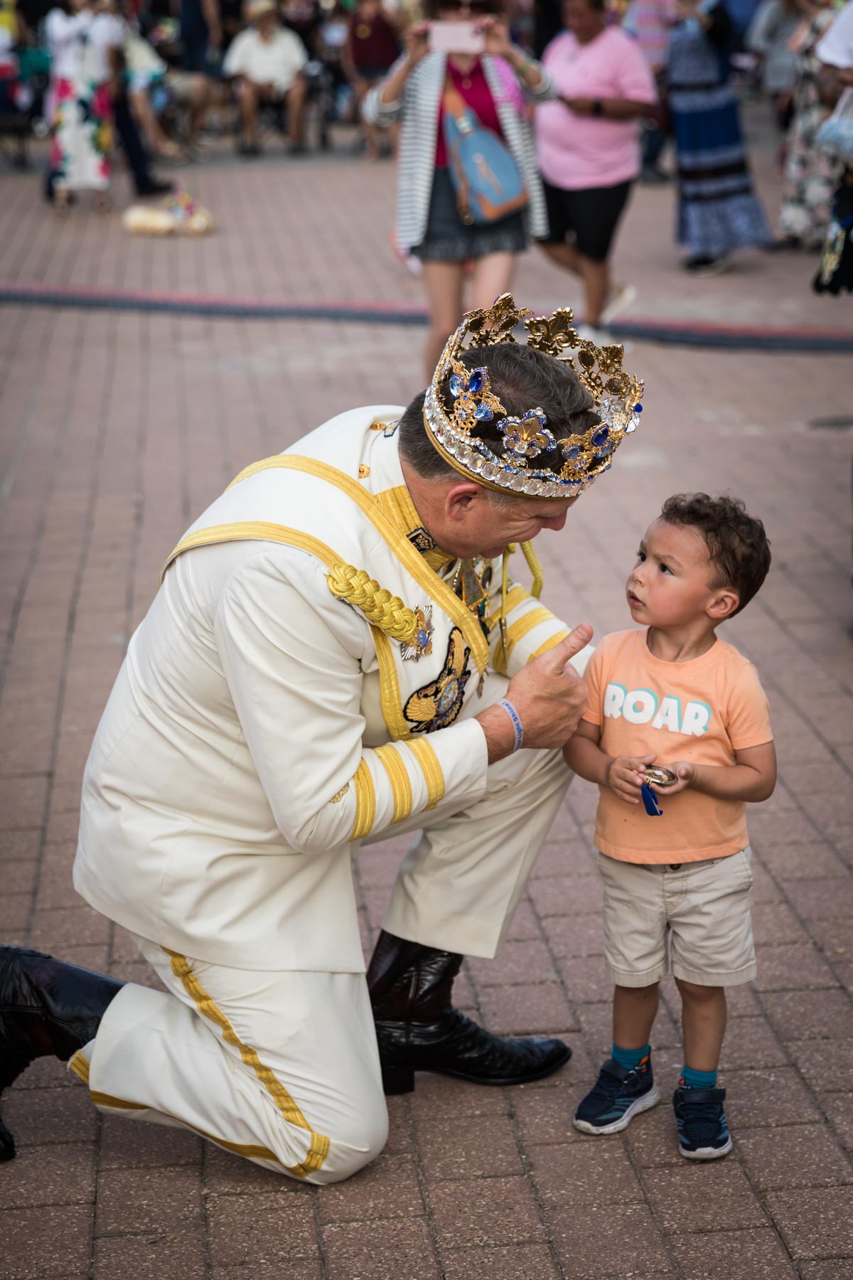 Rey Feo wearing crown and bending down to talk with little boy for an article on the best Fiesta photos