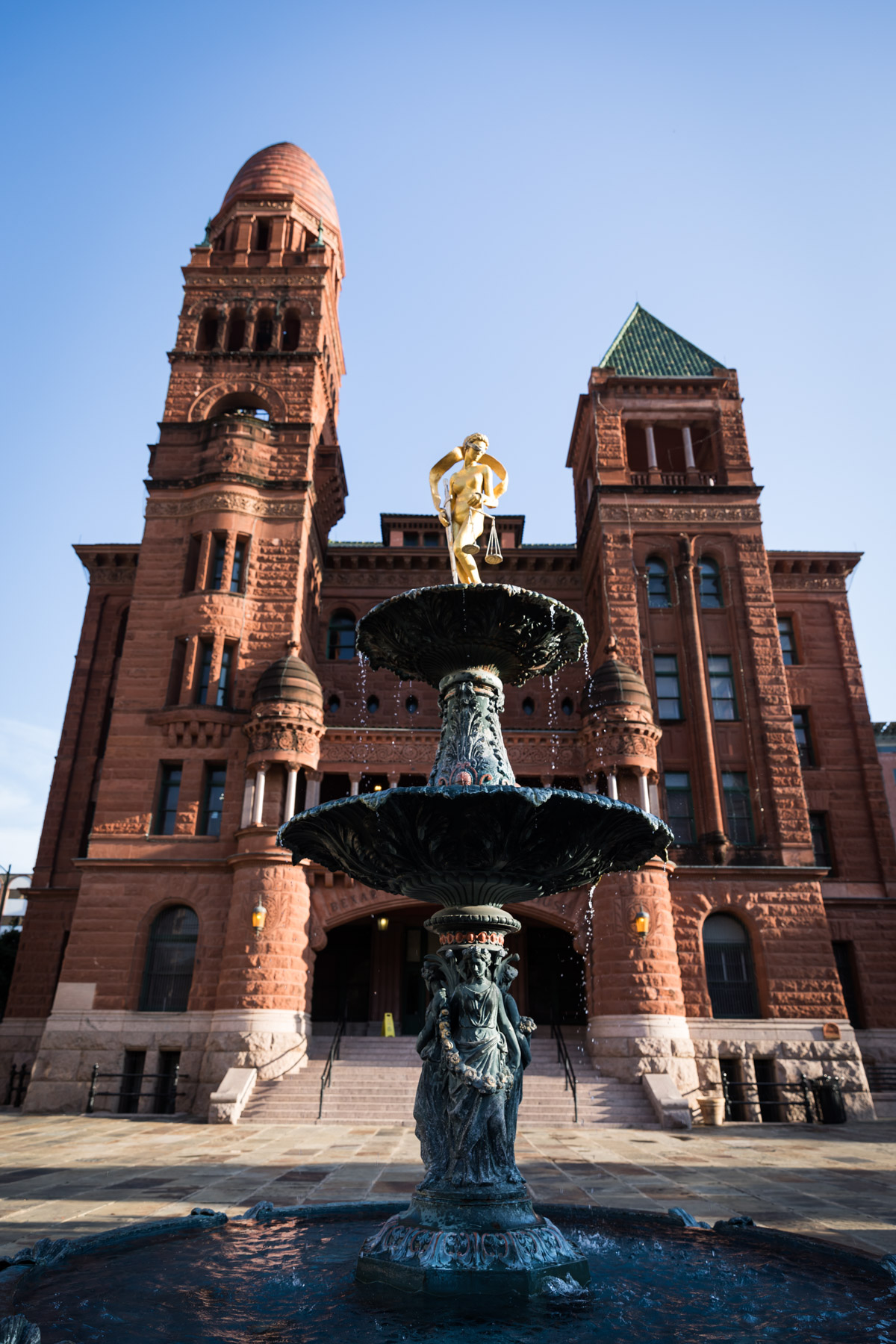 Red brick facade of Bexar County Courthouse with fountain in front for an article on the perfect downtown San Antonio family portrait itinerary
