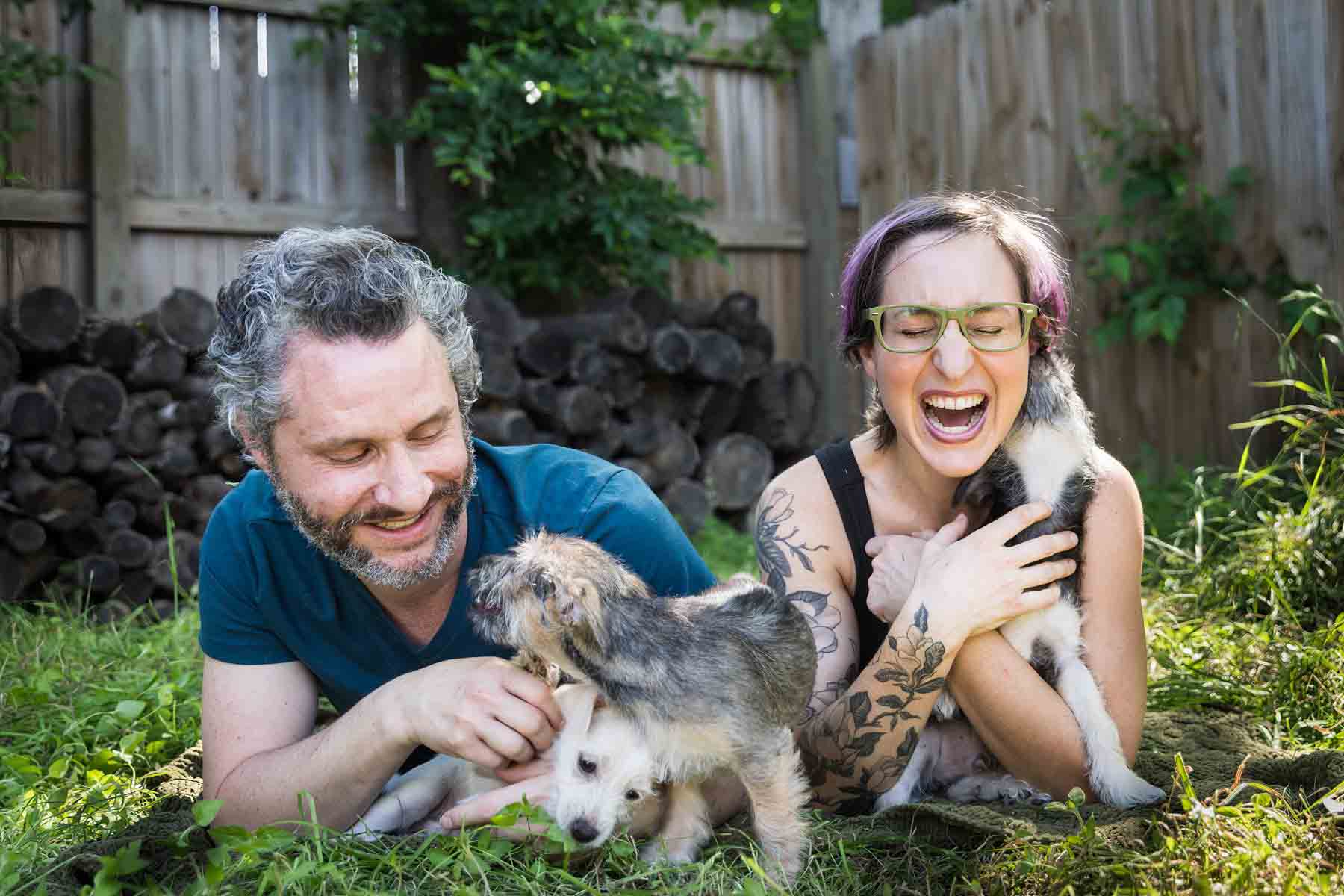 Man and woman lying on ground holding puppies for an article on pet photo tips