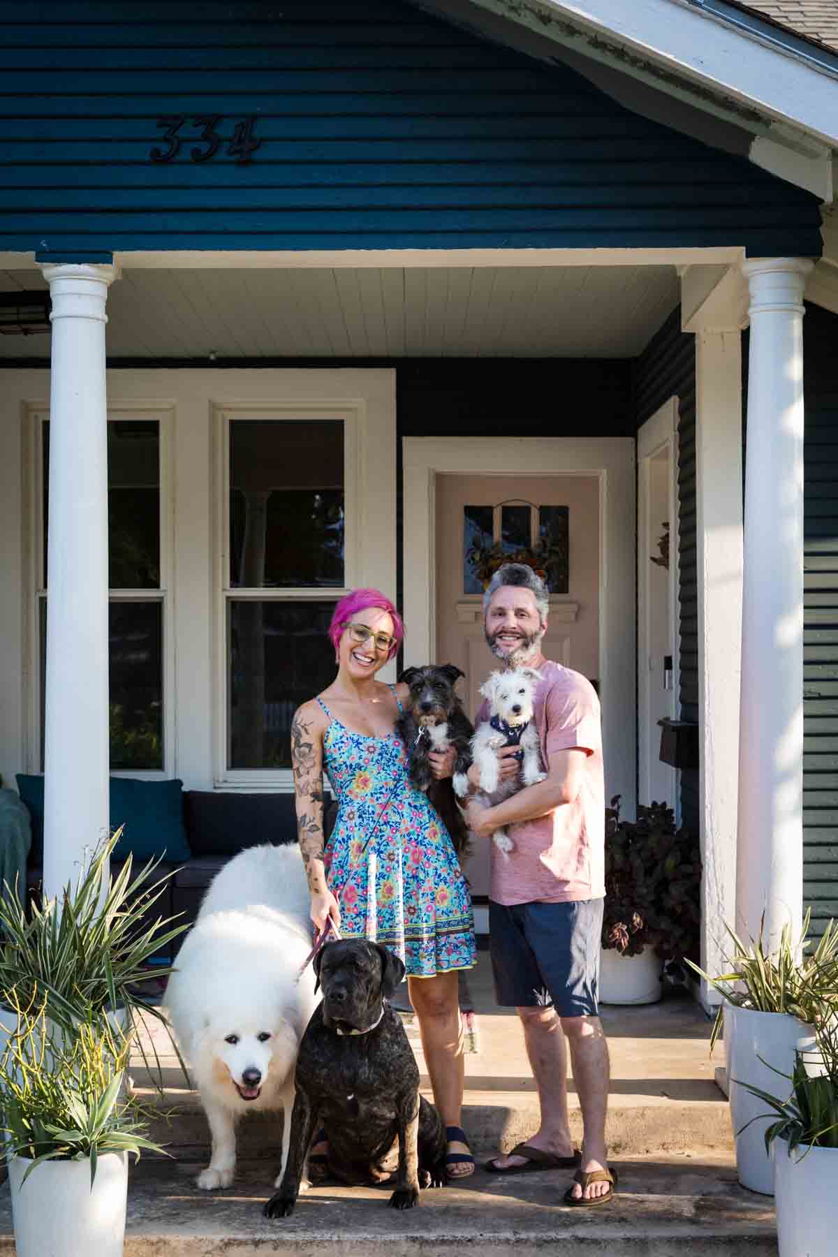 Couple standing in front of home with four dogs for an article on pet photo tips
