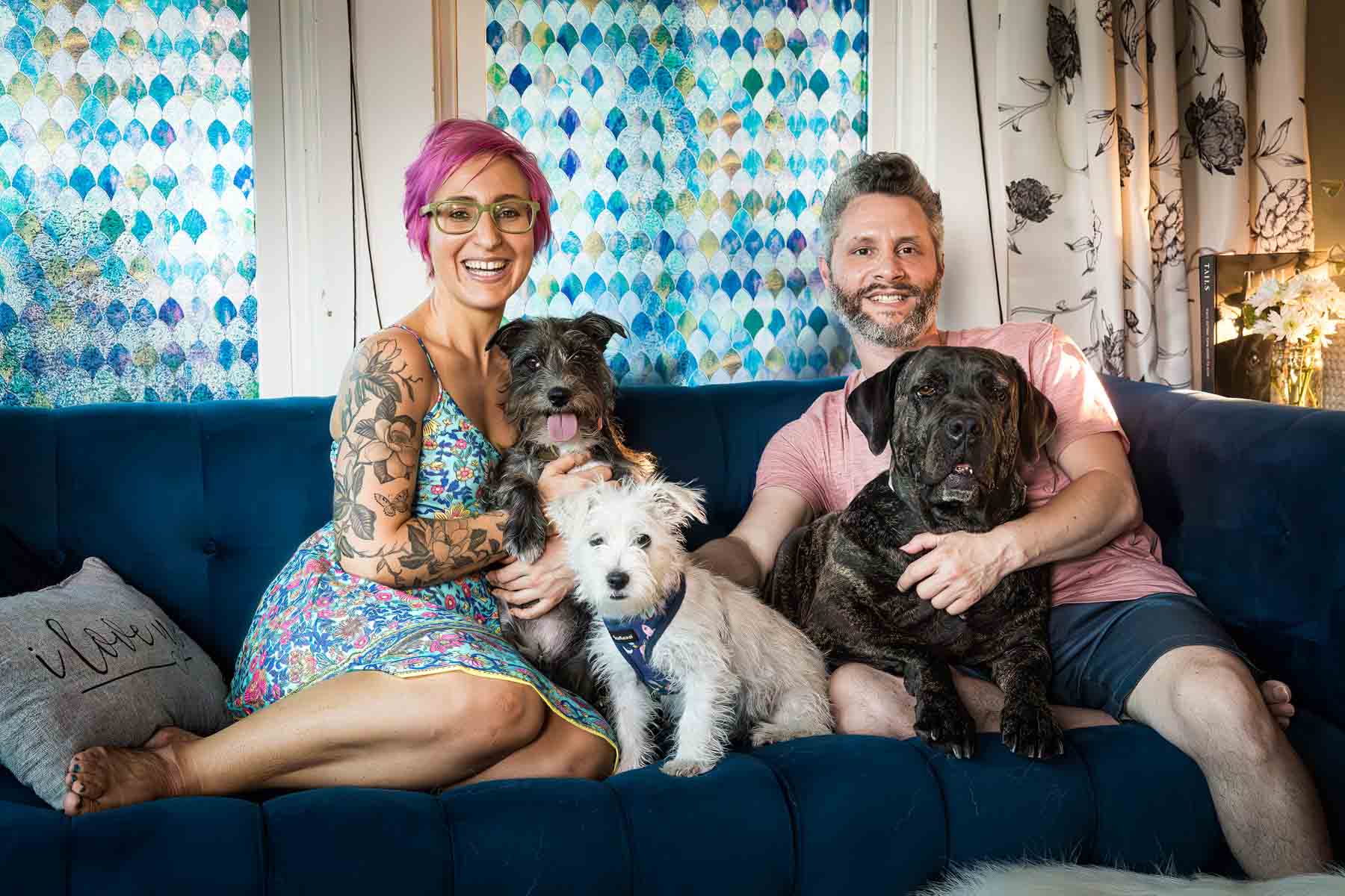 Couple lying on blue couch surrounded by three dogs for an article on pet photo tips