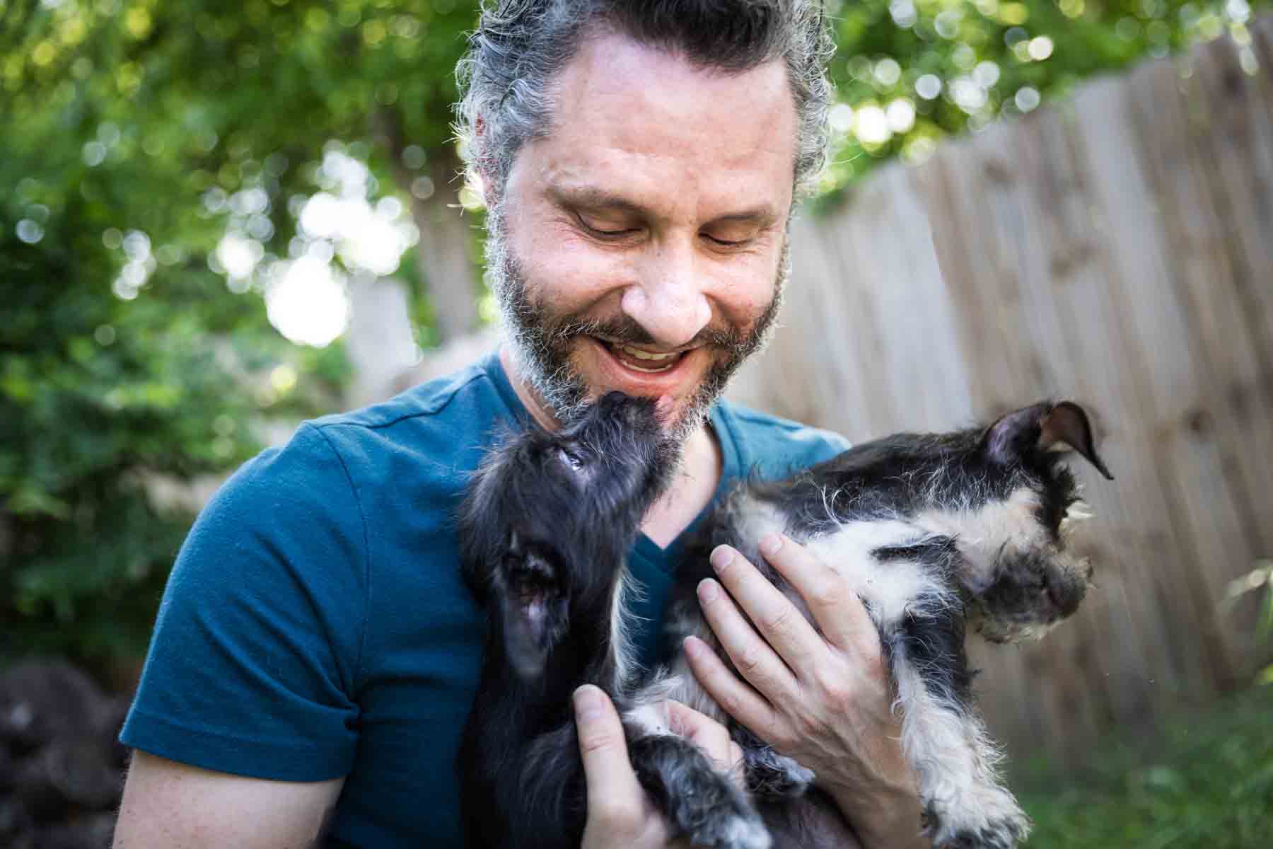 Man with gray hair ad beard holding two puppies for an article on pet photo tips